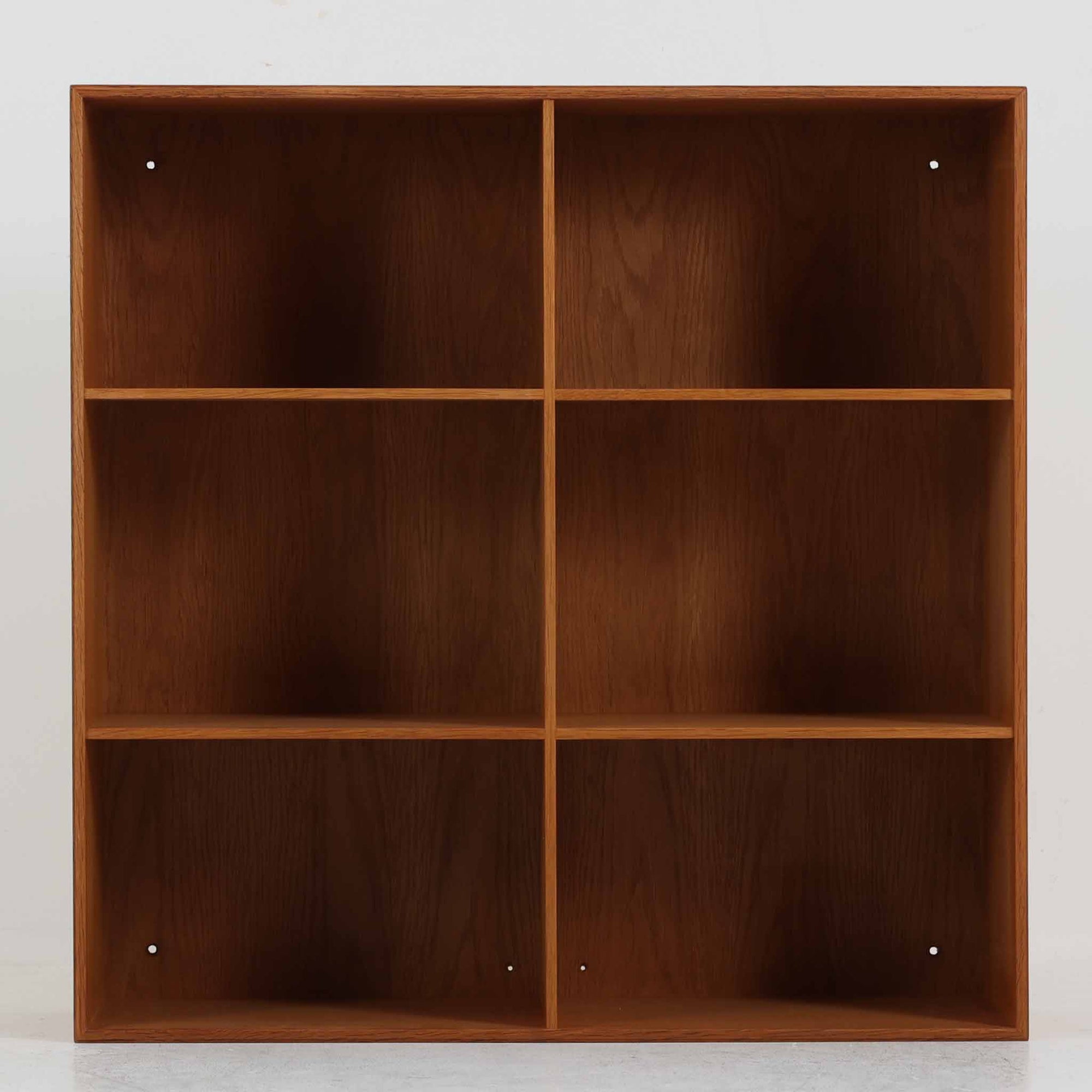 デンマークの建築家Mogens Koch（モーエンス・コッホ）によってデザインされ、名工房Rud. Rasmussen社で製造されたオーク無垢材のブックシェルフです。無駄のない端正なフォルムと精緻な組継ぎ構造が特徴で、堅牢さと美しさを兼ね備えています。ナチュラルなオークの木肌は経年により温かみを増し、シンプルながらも存在感のある佇まいを演出。縦横いずれの向きでも使用でき、複数を組み合わせて自由にレイアウトできる汎用性の高い北欧ビンテージ家具です。