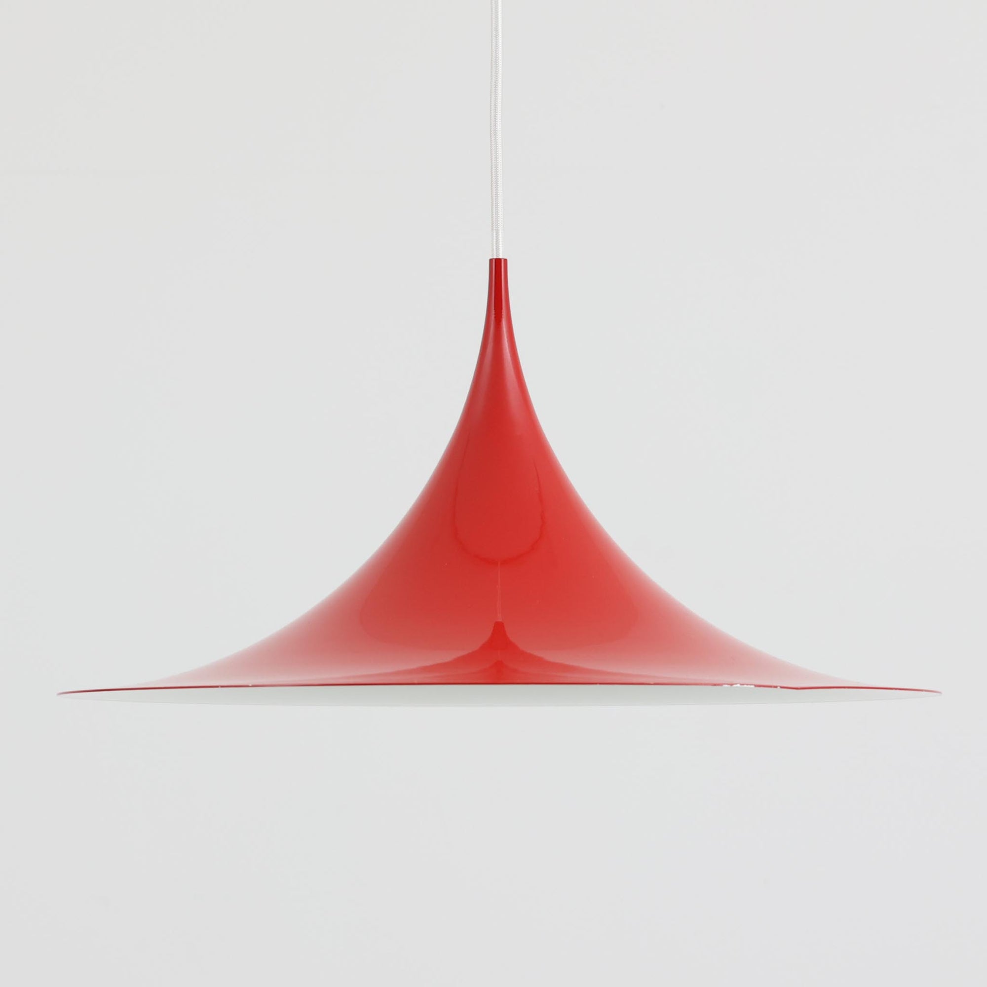 Claus Bonderup & Torsten Thorupによってデザインされ、Fog & Morup社から発表されたペンダントライト「Semi」です。直径47cmの存在感あるサイズと、シャープに絞り込まれた独特のフォルムが特徴です。鮮やかなレッドのカラーが空間にアクセントを与え、点灯時には下方向へ集中的に光を届けつつ、周囲をやわらかく照らします。1960年代に誕生したモダンデザインの象徴的な作品で、シンプルながらも彫刻的な美しさを備えています。北欧ビンテージならではの上質な佇まいで、ダイニングやリビングに華やかな雰囲気を添える一灯です。