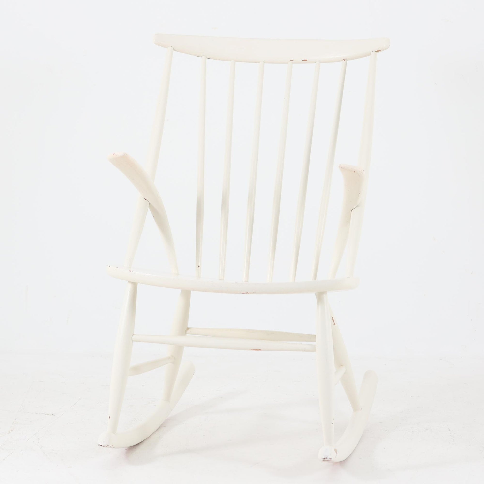 Illum WikkelsoがデザインしEilersen社から製造されたロッキングチェアは、ウィンザーチェアを思わせるスピンドル状の背もたれと、小ぶりなアームが特徴です。軽やかなフレームラインとロッカーの緩やかな揺れが心地よい座り心地を生み出し、読書やリラックスタイムに最適な一脚です。ホワイトペイントは経年により自然な剥がれや味わいが加わり、ビンテージならではの表情をお楽しみいただけます。