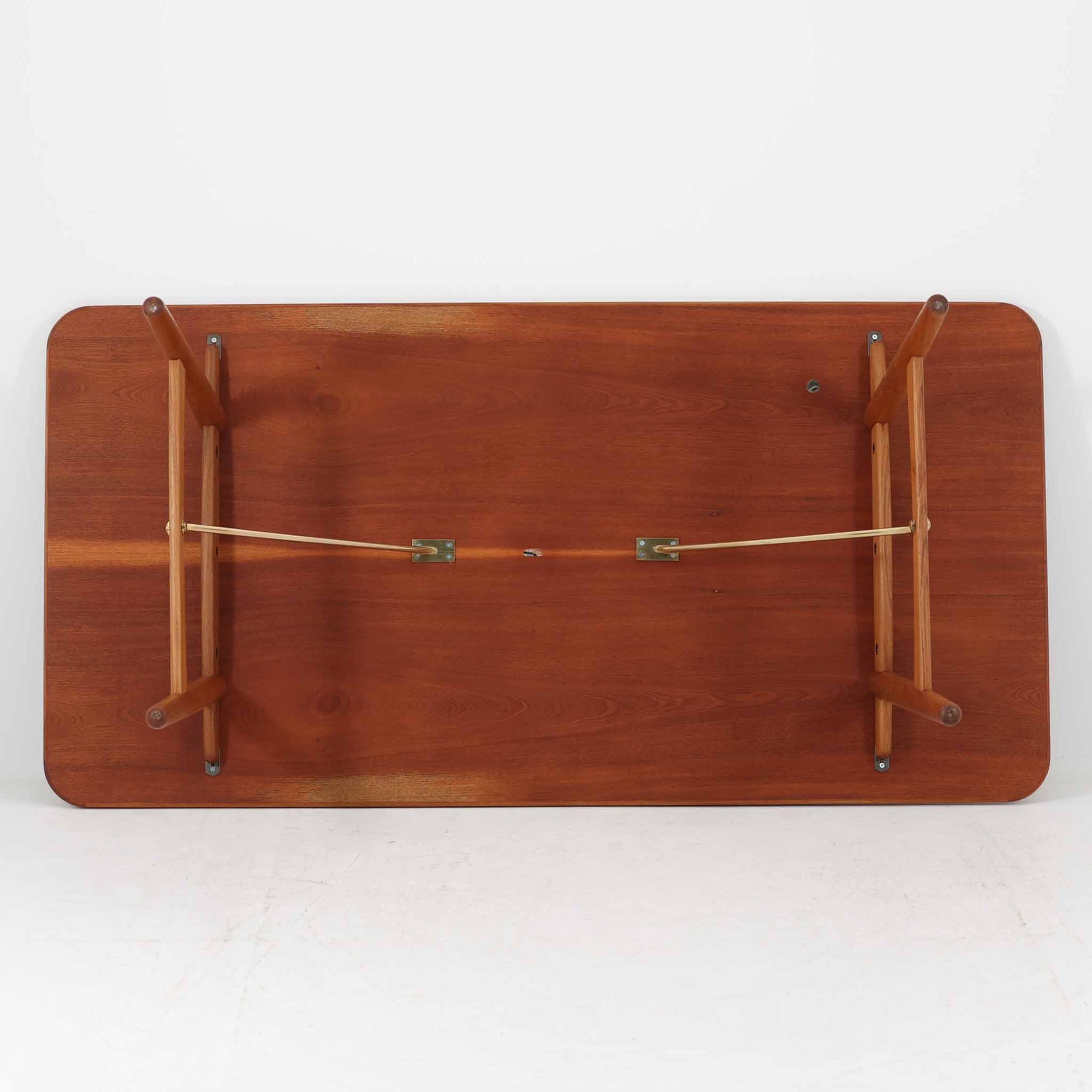 Borge Mogensenがデザインし、Soborg Mobler社より製造されたダイニングテーブル「BM1160」ハンティングテーブルです。現行品はカール・ハンセン社からも展開されていますが、こちらはSoborg社製造によるビンテージ品で、現在では入手が難しいチーク材仕様となっています。幅180cmと現行品よりややコンパクトなサイズ感で、日本の住空間にも取り入れやすい設計です。豊かな木目を持つチーク材の天板に、脚部を支える真鍮製クロスバーを組み合わせることで、堅牢さと美しさを兼ね備えています。角には滑らかな曲線が施され、温かみのある印象を添えつつ、家族や来客を迎える食卓として十分な広さを誇ります。真鍮パーツは構造的強度を高めると同時にビンテージらしい上質なアクセントとなり、シンプルでありながら存在感ある佇まいを演出。北欧家具ならではの実用性とデザイン性が息づき、年月を重ねることでさらに素材の風合いが深まり、空間を豊かに彩ります。