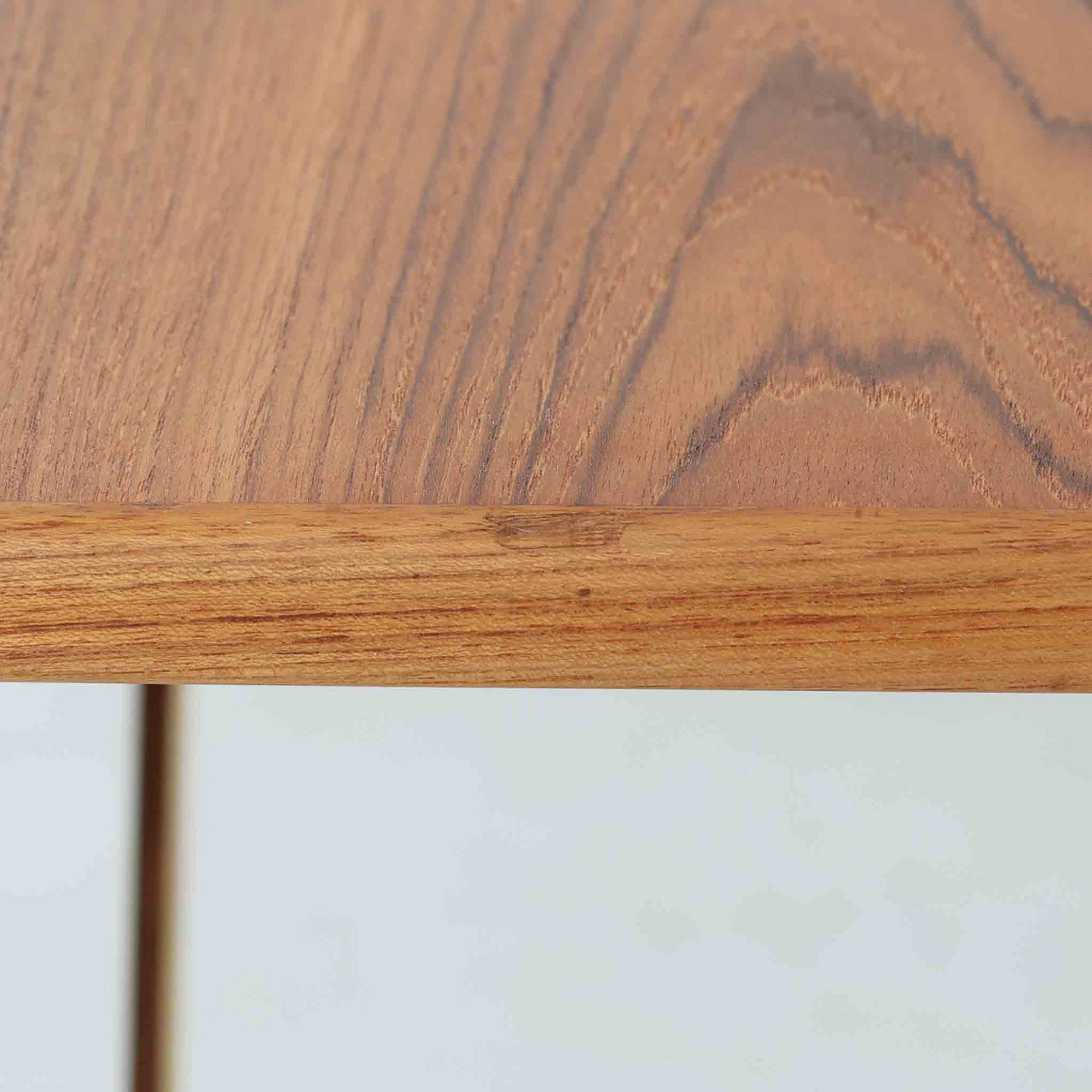 Borge Mogensenがデザインし、Soborg Mobler社より製造されたダイニングテーブル「BM1160」ハンティングテーブルです。現行品はカール・ハンセン社からも展開されていますが、こちらはSoborg社製造によるビンテージ品で、現在では入手が難しいチーク材仕様となっています。幅180cmと現行品よりややコンパクトなサイズ感で、日本の住空間にも取り入れやすい設計です。豊かな木目を持つチーク材の天板に、脚部を支える真鍮製クロスバーを組み合わせることで、堅牢さと美しさを兼ね備えています。角には滑らかな曲線が施され、温かみのある印象を添えつつ、家族や来客を迎える食卓として十分な広さを誇ります。真鍮パーツは構造的強度を高めると同時にビンテージらしい上質なアクセントとなり、シンプルでありながら存在感ある佇まいを演出。北欧家具ならではの実用性とデザイン性が息づき、年月を重ねることでさらに素材の風合いが深まり、空間を豊かに彩ります。