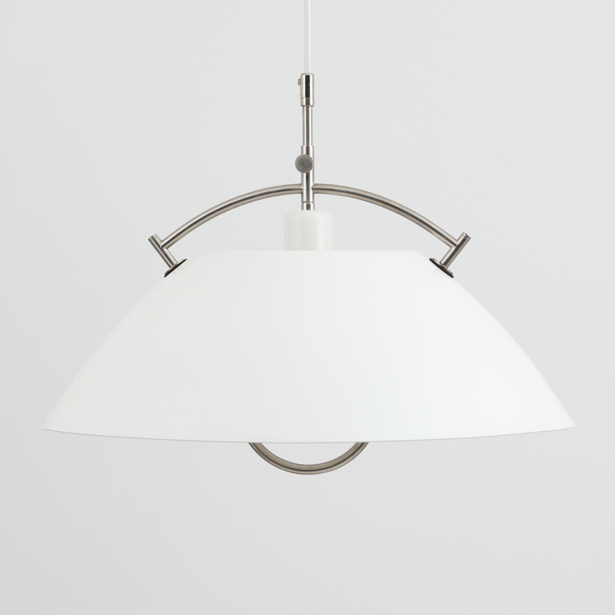 Pandul（パンドゥル）社が正規製造している、ハンス・J・ウェグナー（Hans J. Wegner）デザインのペンダントライト「JH604」です。1960年代にLouis Poulsen（ルイスポールセン）社で製造されていたモデルで、ウェグナーが自邸のためにデザインしたことでも知られています。直径50cmの存在感あるフォルムと、アルミ製シェードとステンレス製アームによる軽やかで堅牢な構造は、北欧デザインらしい機能美を体現。点灯時には下方向だけでなくシェード上部の隙間からも光が柔らかく漏れ、空間に奥行きを与えます。Pandulは1982年にデンマークで設立され、Louis Poulsenから受け継いだ名作を当時のデザインと品質を尊重して製造しているブランドです。なお、本品はプラスチック製コードリールが欠品しておりますが、全体として良好なコンディションを保っています。ヴィンテージデザインの魅力と現行製造ならではの安心感を兼ね備えた、北欧デザインを象徴する一灯です。