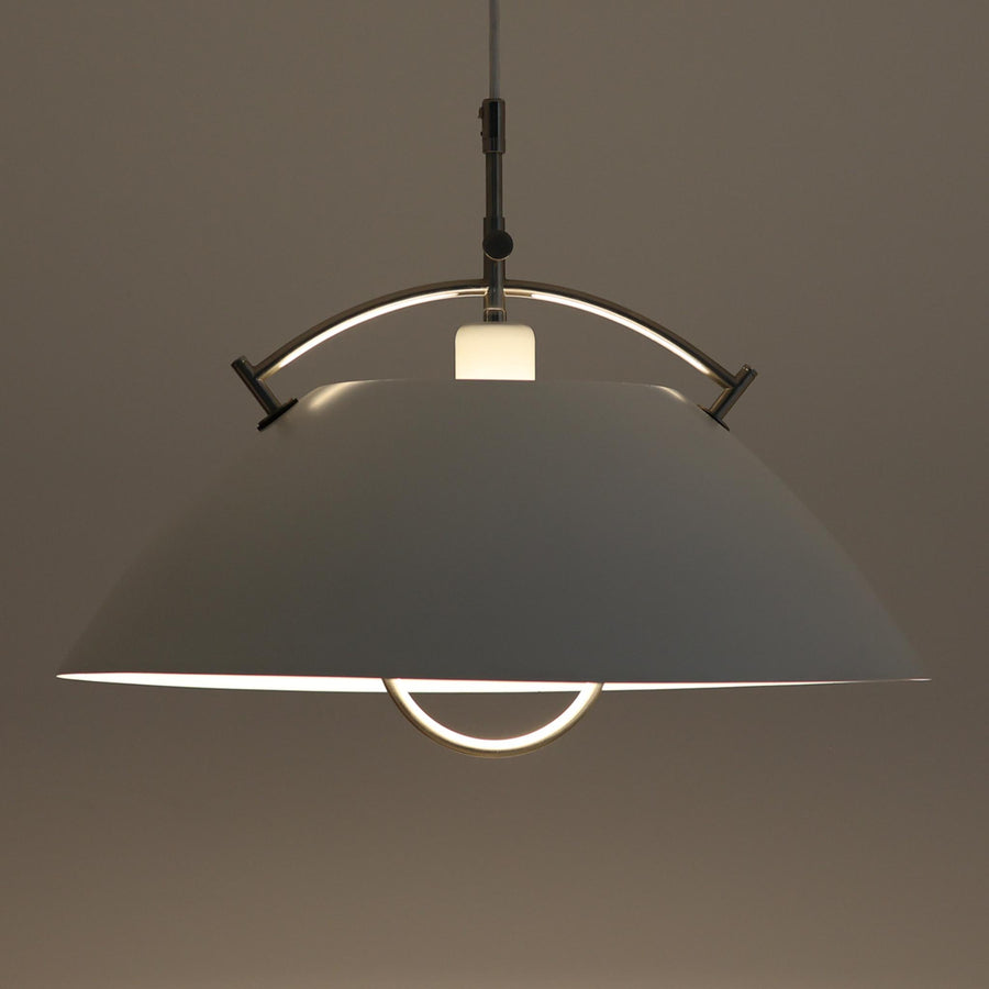 Pandul（パンドゥル）社が正規製造している、ハンス・J・ウェグナー（Hans J. Wegner）デザインのペンダントライト「JH604」です。1960年代にLouis Poulsen（ルイスポールセン）社で製造されていたモデルで、ウェグナーが自邸のためにデザインしたことでも知られています。直径50cmの存在感あるフォルムと、アルミ製シェードとステンレス製アームによる軽やかで堅牢な構造は、北欧デザインらしい機能美を体現。点灯時には下方向だけでなくシェード上部の隙間からも光が柔らかく漏れ、空間に奥行きを与えます。Pandulは1982年にデンマークで設立され、Louis Poulsenから受け継いだ名作を当時のデザインと品質を尊重して製造しているブランドです。なお、本品はプラスチック製コードリールが欠品しておりますが、全体として良好なコンディションを保っています。ヴィンテージデザインの魅力と現行製造ならではの安心感を兼ね備えた、北欧デザインを象徴する一灯です。