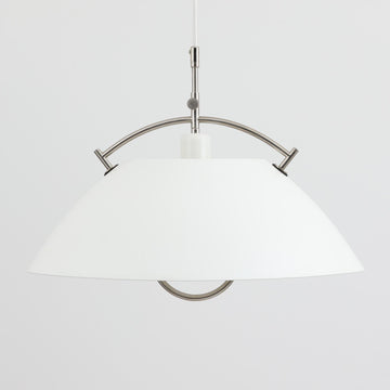 Pandul（パンドゥル）社が正規製造している、ハンス・J・ウェグナー（Hans J. Wegner）デザインのペンダントライト「JH604」です。1960年代にLouis Poulsen（ルイスポールセン）社で製造されていたモデルで、ウェグナーが自邸のためにデザインしたことでも知られています。直径50cmの存在感あるフォルムと、アルミ製シェードとステンレス製アームによる軽やかで堅牢な構造は、北欧デザインらしい機能美を体現。点灯時には下方向だけでなくシェード上部の隙間からも光が柔らかく漏れ、空間に奥行きを与えます。Pandulは1982年にデンマークで設立され、Louis Poulsenから受け継いだ名作を当時のデザインと品質を尊重して製造しているブランドです。なお、本品はプラスチック製コードリールが欠品しておりますが、全体として良好なコンディションを保っています。ヴィンテージデザインの魅力と現行製造ならではの安心感を兼ね備えた、北欧デザインを象徴する一灯です。