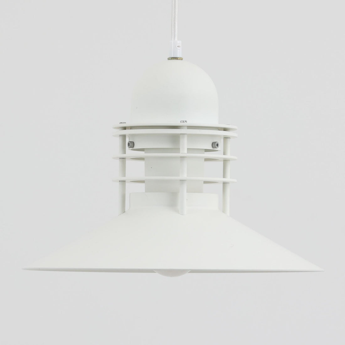Alfred HomannとOle V. Kjaerによってデザインされ、Louis Poulsen社から製造されたペンダントライト「Nyhavn」は、直径31cmのコンパクトなサイズながらも力強い存在感を放ちます。メタル素材を用いたシェードとガード付きの構造は、港町の灯りを思わせる堅牢で印象的なデザインで、光源を柔らかく拡散しつつ下方をしっかりと照らします。シンプルな中に建築的な要素を感じさせる造形は、ダイニングや玄関、カウンター上など幅広い空間で活躍し、北欧ビンテージならではの実用性と希少性を兼ね備えています。