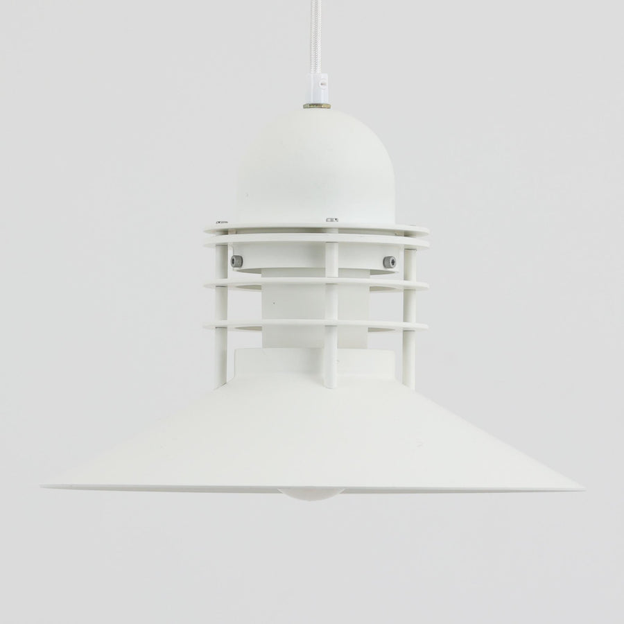 Alfred HomannとOle V. Kjaerによってデザインされ、Louis Poulsen社から製造されたペンダントライト「Nyhavn」は、直径31cmのコンパクトなサイズながらも力強い存在感を放ちます。メタル素材を用いたシェードとガード付きの構造は、港町の灯りを思わせる堅牢で印象的なデザインで、光源を柔らかく拡散しつつ下方をしっかりと照らします。シンプルな中に建築的な要素を感じさせる造形は、ダイニングや玄関、カウンター上など幅広い空間で活躍し、北欧ビンテージならではの実用性と希少性を兼ね備えています。