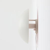 Poul Henningsenがデザインし、Louis Poulsen社から発表されたウォールランプ「PH ハット」直径30cmです。スチール製の半円形シェードは内側を淡いピンク色に仕上げ、点灯時には柔らかで温かみのある光を壁面に広げます。シンプルながら緻密に計算された光の効果はヘニングセンならではの魅力で、寝室や廊下、リビングの補助照明として最適です。1950年代に誕生したモデルは現在でも高く評価されており、ビンテージならではの風合いと希少性を備えています。元々は2サイズ展開で、本品は現行品には存在しない大サイズの希少モデルです。