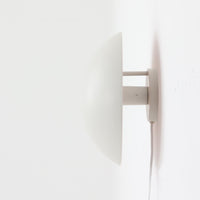 Poul Henningsenがデザインし、Louis Poulsen社から発表されたウォールランプ「PH ハット」直径30cmです。スチール製の半円形シェードは内側を淡いピンク色に仕上げ、点灯時には柔らかで温かみのある光を壁面に広げます。シンプルながら緻密に計算された光の効果はヘニングセンならではの魅力で、寝室や廊下、リビングの補助照明として最適です。1950年代に誕生したモデルは現在でも高く評価されており、ビンテージならではの風合いと希少性を備えています。元々は2サイズ展開で、本品は現行品には存在しない大サイズの希少モデルです。