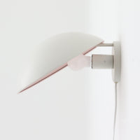 Poul Henningsenがデザインし、Louis Poulsen社から発表されたウォールランプ「PH ハット」直径30cmです。スチール製の半円形シェードは内側を淡いピンク色に仕上げ、点灯時には柔らかで温かみのある光を壁面に広げます。シンプルながら緻密に計算された光の効果はヘニングセンならではの魅力で、寝室や廊下、リビングの補助照明として最適です。1950年代に誕生したモデルは現在でも高く評価されており、ビンテージならではの風合いと希少性を備えています。元々は2サイズ展開で、本品は現行品には存在しない大サイズの希少モデルです。