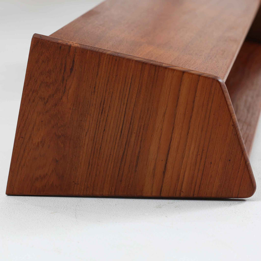 デンマークの家具メーカー、Aksel Kjersgaard（アクセル・キアスゴー）によるチーク無垢材のウォールシェルフです。無駄を削ぎ落とした直線的なデザインと、面取りされた角の柔らかさが美しく調和し、上質な北欧モダンを感じさせます。細やかな木目が際立つチーク無垢材は、経年とともに深みを増し、時間とともに味わいを楽しめます。本や小物をディスプレイするだけでなく、玄関や寝室の壁面収納としても便利。職人技が光る洗練されたシェルフです。