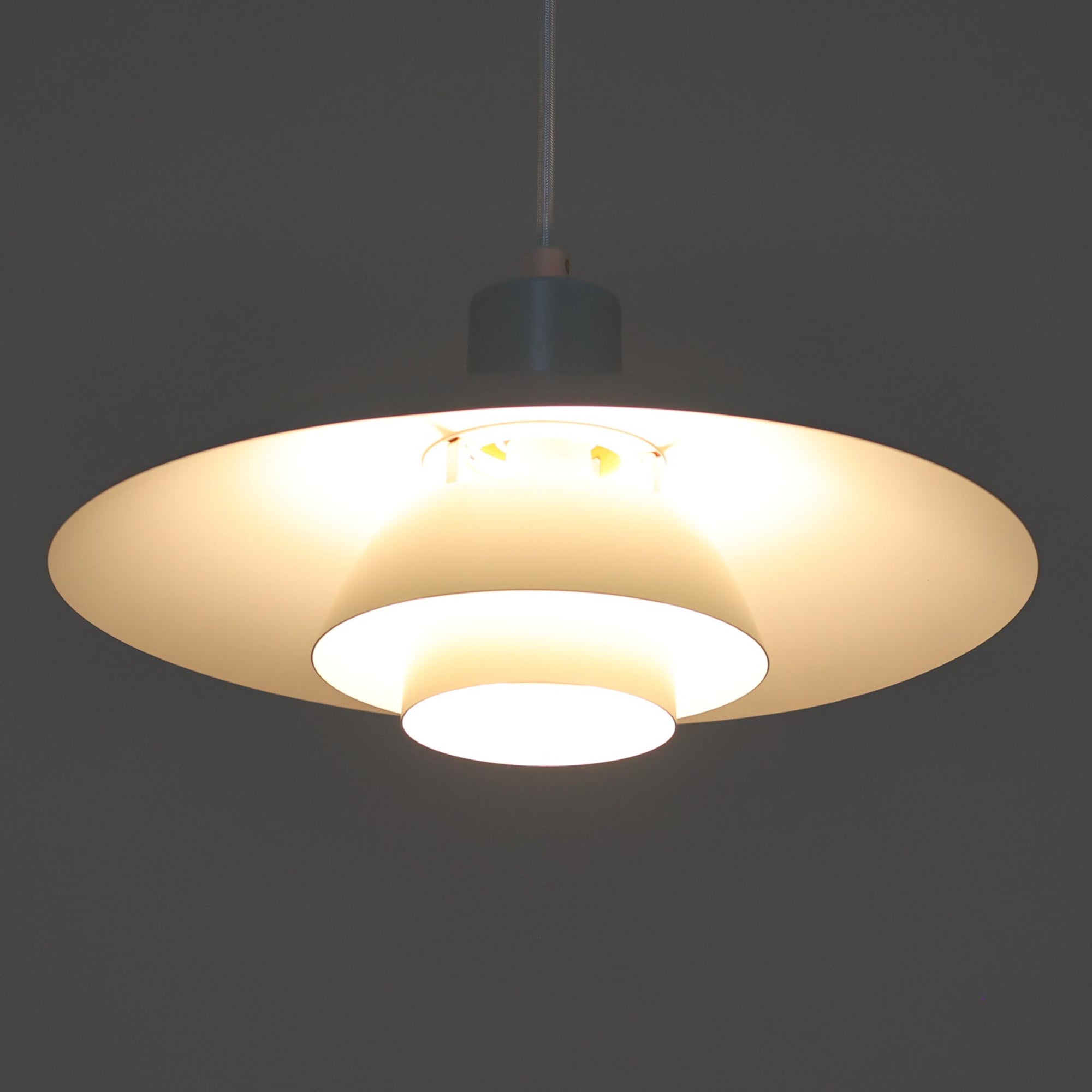 北欧より買い付けたLouis Poulsen社製「PH4」は、Poul Henningsenによる名作照明で、直径40cmの程よいサイズとアルミの軽やかな質感が魅力です。PH5と並ぶ人気を誇り、3枚シェード構造が光を柔らかく拡散し落ち着いた空間を演出します。経年の風合いも楽しめ、ダイニングやリビング、書斎や寝室まで幅広く活躍するビンテージ品です。