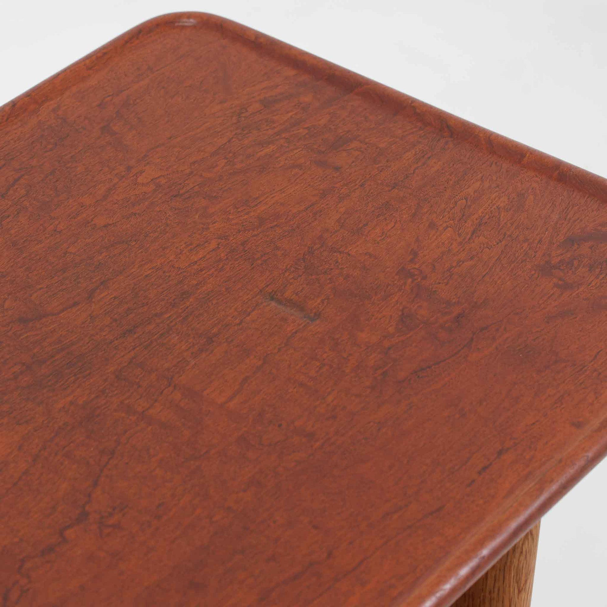 Hans J. WegnerがAndreas Tuckのために手掛けたAT10センターテーブルは、チーク材の天板にオーク材のフレーム、ラタン張りの棚板を組み合わせた、素材使いの美しさが際立つ北欧ビンテージの名作です。直線を基調とした端正なプロポーションの中に、天板縁のやわらかな丸みや、軽やかに抜け感を生むラタン棚が配され、視覚的にも圧迫感のない佇まいに仕上げられています。幅160cmのゆとりあるサイズはリビングの主役として使いやすく、雑誌や小物を収納できる実用性も備え、経年変化により深みを増した木肌が空間に上質な落ち着きをもたらします。なお、天板には反りがあり、大きめのへこみも見られるため、その点を考慮した価格設定としておりますが、ご使用には問題なく、ビンテージならではの風合いとしてご理解いただける方におすすめの一台です。