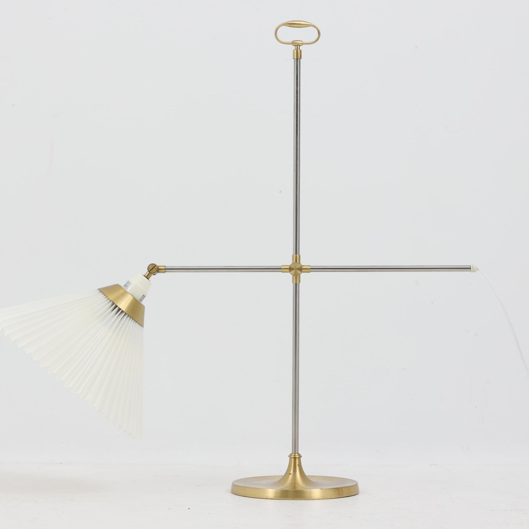 Esben Klintによるデザインで、Le Klint（レ・クリント）より発表されたテーブルランプModel 319です。真鍮とスチールを組み合わせた構造は、堅牢さと洗練された印象を兼ね備え、ハンドメイドのプリーツシェードが柔らかい光を拡散します。高さ75cmの程よいサイズ感とクロスバー構造による可動性が特徴で、デスクやリビングでの読書灯としても実用的です。経年による真鍮の風合いがビンテージらしい魅力を引き立て、空間にクラシカルで上質な雰囲気をもたらします。