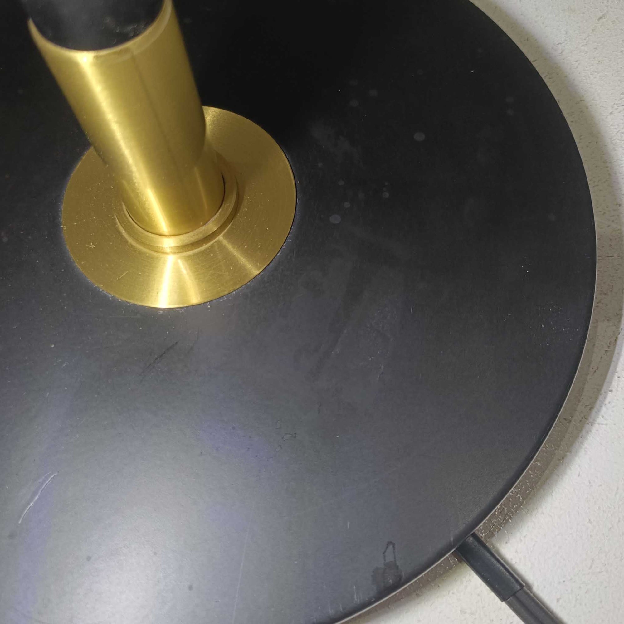 Aage Petersenによるデザインで、Le Klint社より発表されたモデル352のテーブルランプです。高さ62～85cmの昇降機能を備え、使用シーンに合わせて調整可能なのが魅力です。黒塗装のスチール支柱に真鍮パーツがアクセントとなり、プリーツ加工が美しい紙製シェードからは柔らかな光が広がります。特に点灯時にはシェードを透過して漏れる灯りが印象的で、空間を上品に演出します。現在は廃盤となっており、ビンテージ品のみ入手可能なモデルです。