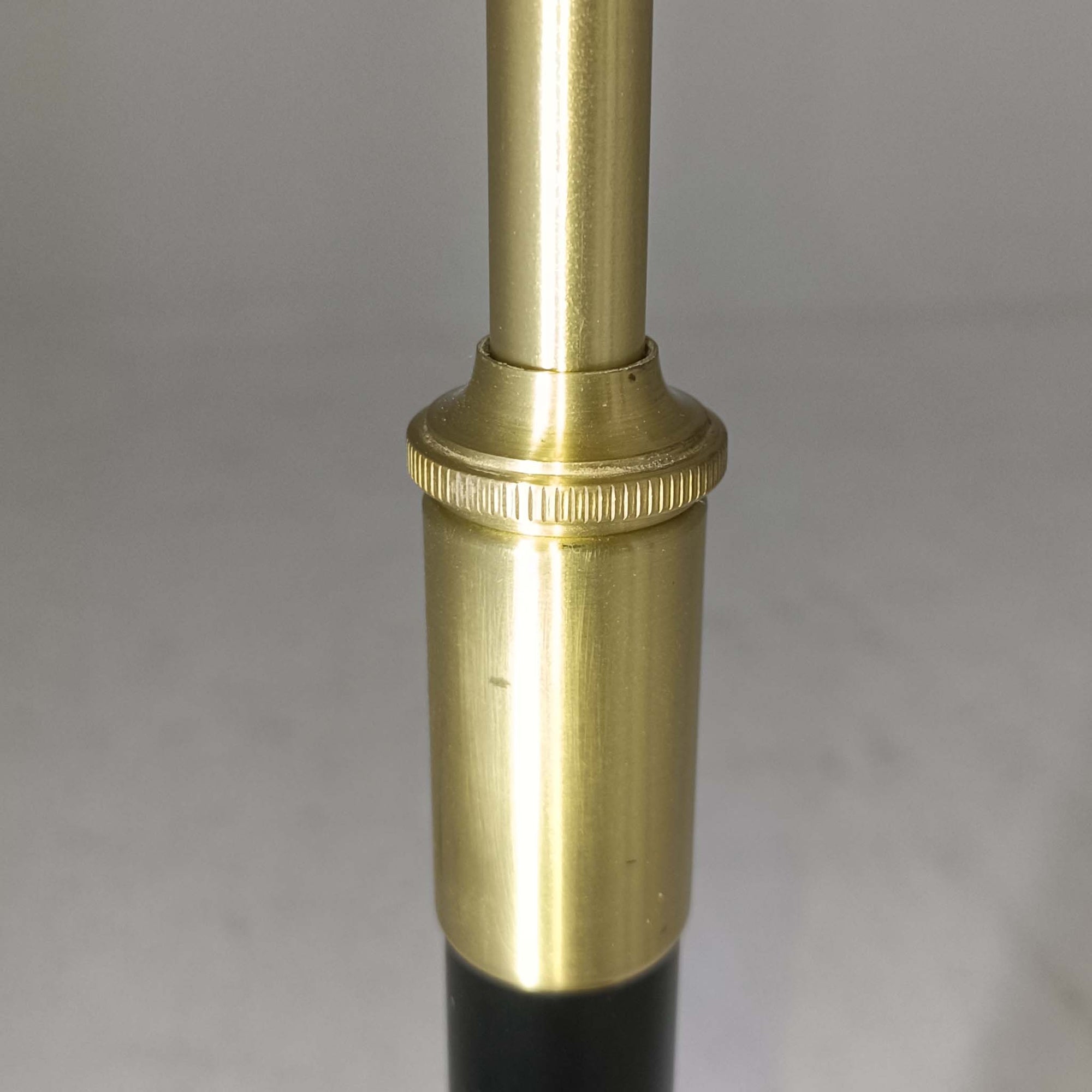 Aage Petersenによるデザインで、Le Klint社より発表されたモデル352のテーブルランプです。高さ62～85cmの昇降機能を備え、使用シーンに合わせて調整可能なのが魅力です。黒塗装のスチール支柱に真鍮パーツがアクセントとなり、プリーツ加工が美しい紙製シェードからは柔らかな光が広がります。特に点灯時にはシェードを透過して漏れる灯りが印象的で、空間を上品に演出します。現在は廃盤となっており、ビンテージ品のみ入手可能なモデルです。