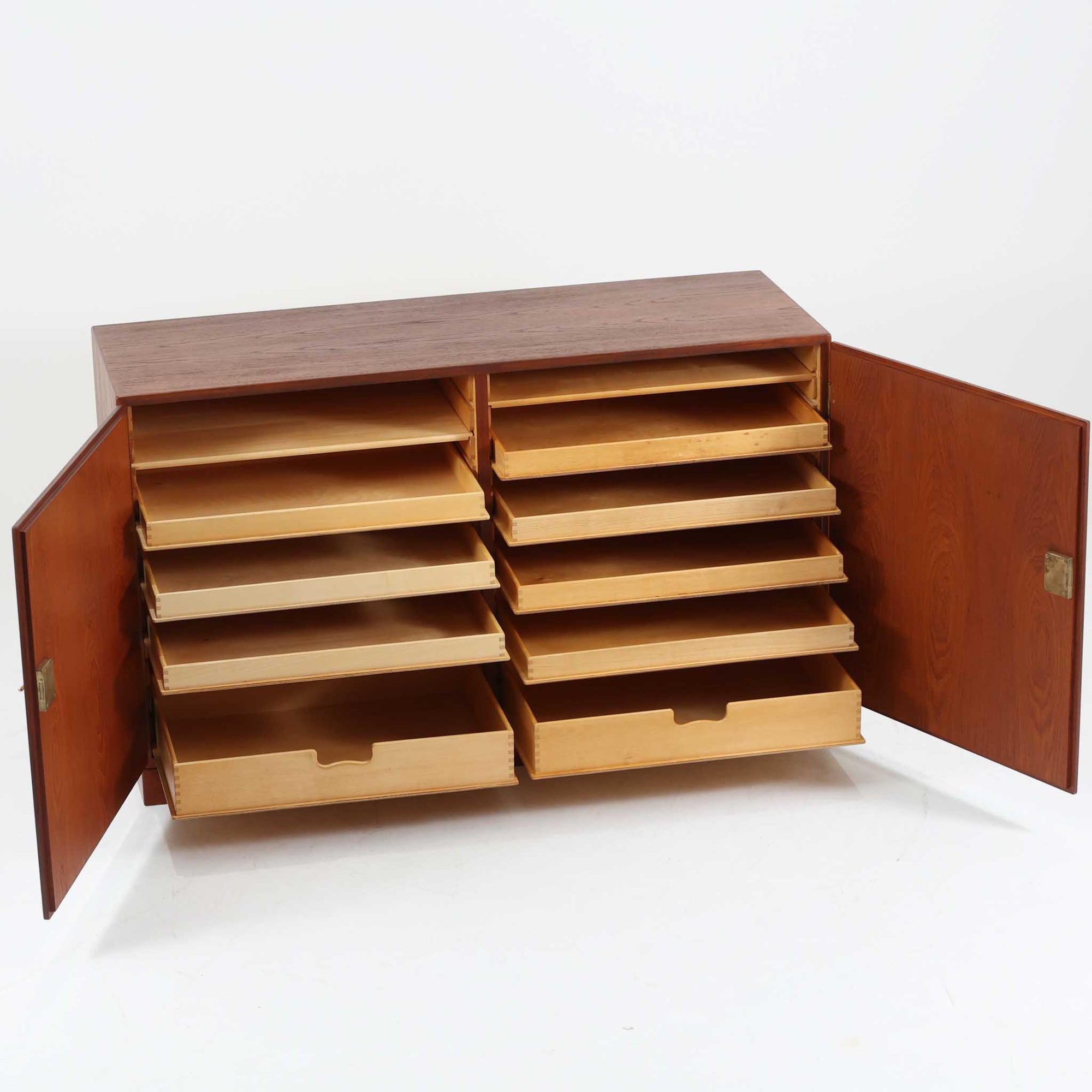 Borge Mogensenがデザインし、FDB Moblerにより製作されたModel 232のキャビネットです。チーク材の美しい木目を活かした端正な外観と、鍵がそのまま取っ手として機能するユニークな構造が特徴です。内部には引き出しと棚板が備えられ、位置調整や取り外しが可能なため用途に合わせて柔軟に収納できます。幅122cmの扱いやすいサイズで、リビングや書斎など様々な空間で活躍する、実用性と北欧デザインの魅力を兼ね備えたビンテージ家具です。