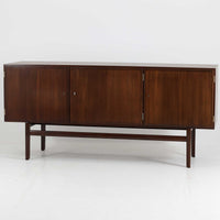 Ole Wanscher（オーレ・ヴァンシャー）がデザインし、P.Jeppesen社より製造された「Rungstedlund」キャビネットです。端正な直線構成と細く伸びた脚部が特徴で、マホガニー材特有の深い色調と気品ある木目が空間に落ち着きをもたらします。内部は棚板とトレイが効率よく配置され、食器から書類収納まで幅広く活用可能。上質な素材使いと精巧な造り込みはヴァンシャー作品ならではで、経年により全体に落ち着いた色調へと変化しており、現地デンマークのオークションで入手した確かな出自を持つ個体です。