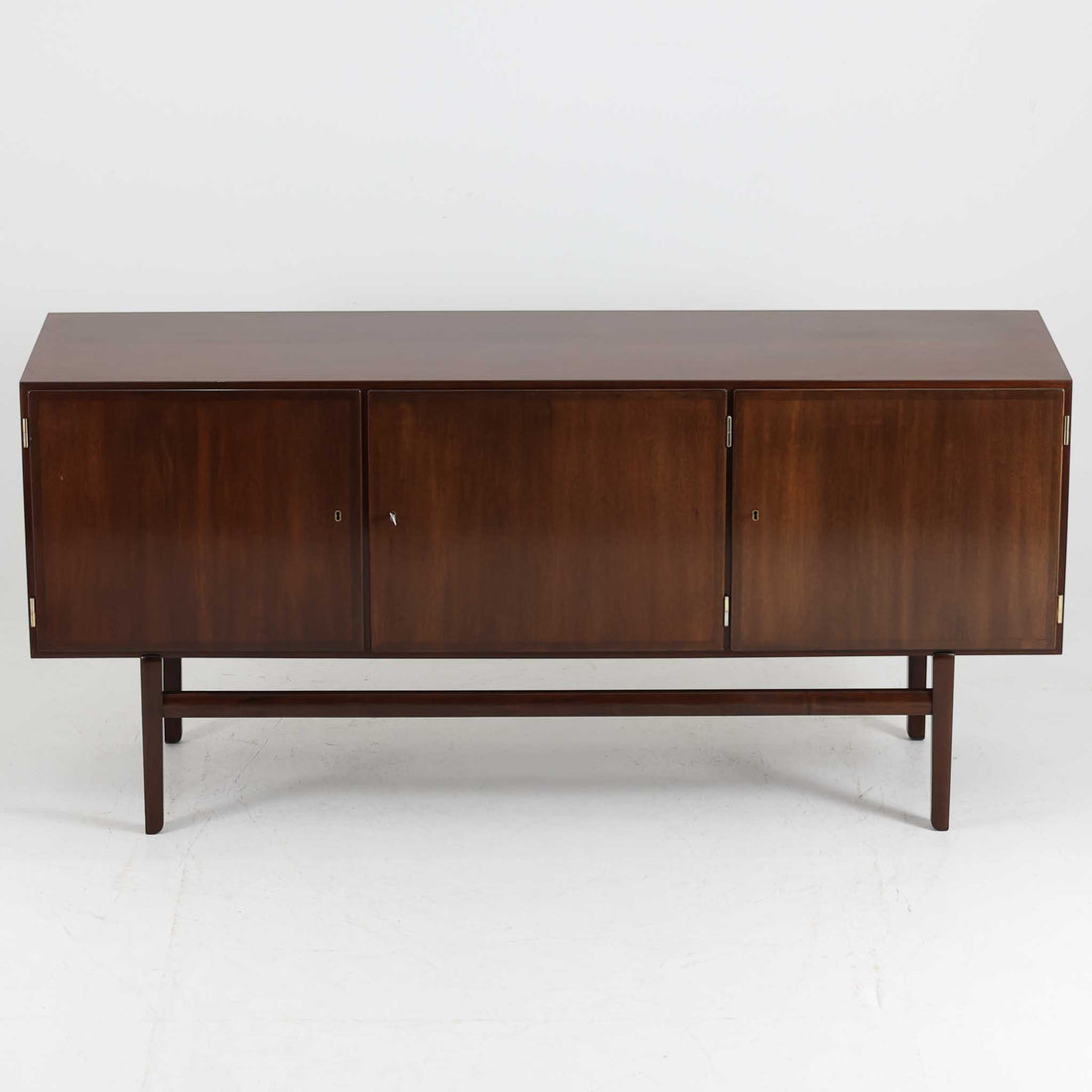 Ole Wanscher（オーレ・ヴァンシャー）がデザインし、P.Jeppesen社より製造された「Rungstedlund」キャビネットです。端正な直線構成と細く伸びた脚部が特徴で、マホガニー材特有の深い色調と気品ある木目が空間に落ち着きをもたらします。内部は棚板とトレイが効率よく配置され、食器から書類収納まで幅広く活用可能。上質な素材使いと精巧な造り込みはヴァンシャー作品ならではで、経年により全体に落ち着いた色調へと変化しており、現地デンマークのオークションで入手した確かな出自を持つ個体です。