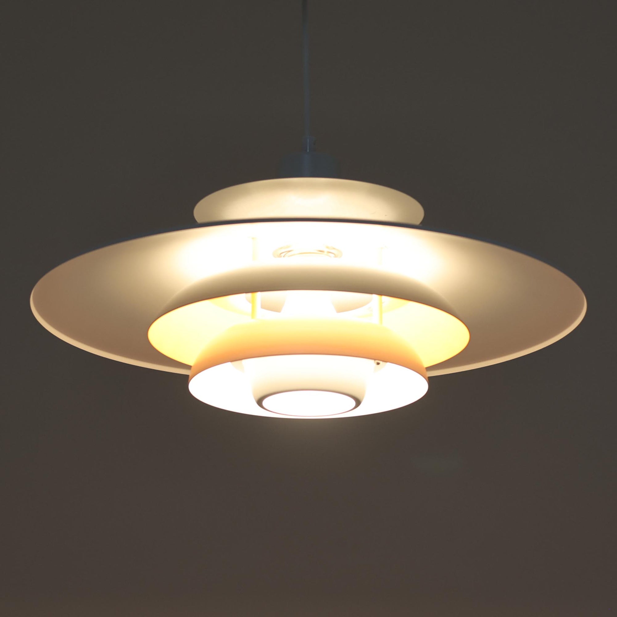 Jeka Metaltryk社製のペンダントライト「Sofie」です。直径48cmと大きめのサイズで、複数枚のシェードを重ねた構造が特徴的です。スチール素材のしっかりとした造りで、点灯時には光が柔らかく分散し、眩しさを抑えつつ空間を明るく照らします。内側に施された温かみのある色合いが、照明に柔らかなニュアンスを加え、ダイニングやリビングのメインライトとして存在感を放ちます。シンプルながらも洗練された北欧デザインを感じさせるビンテージアイテムです。