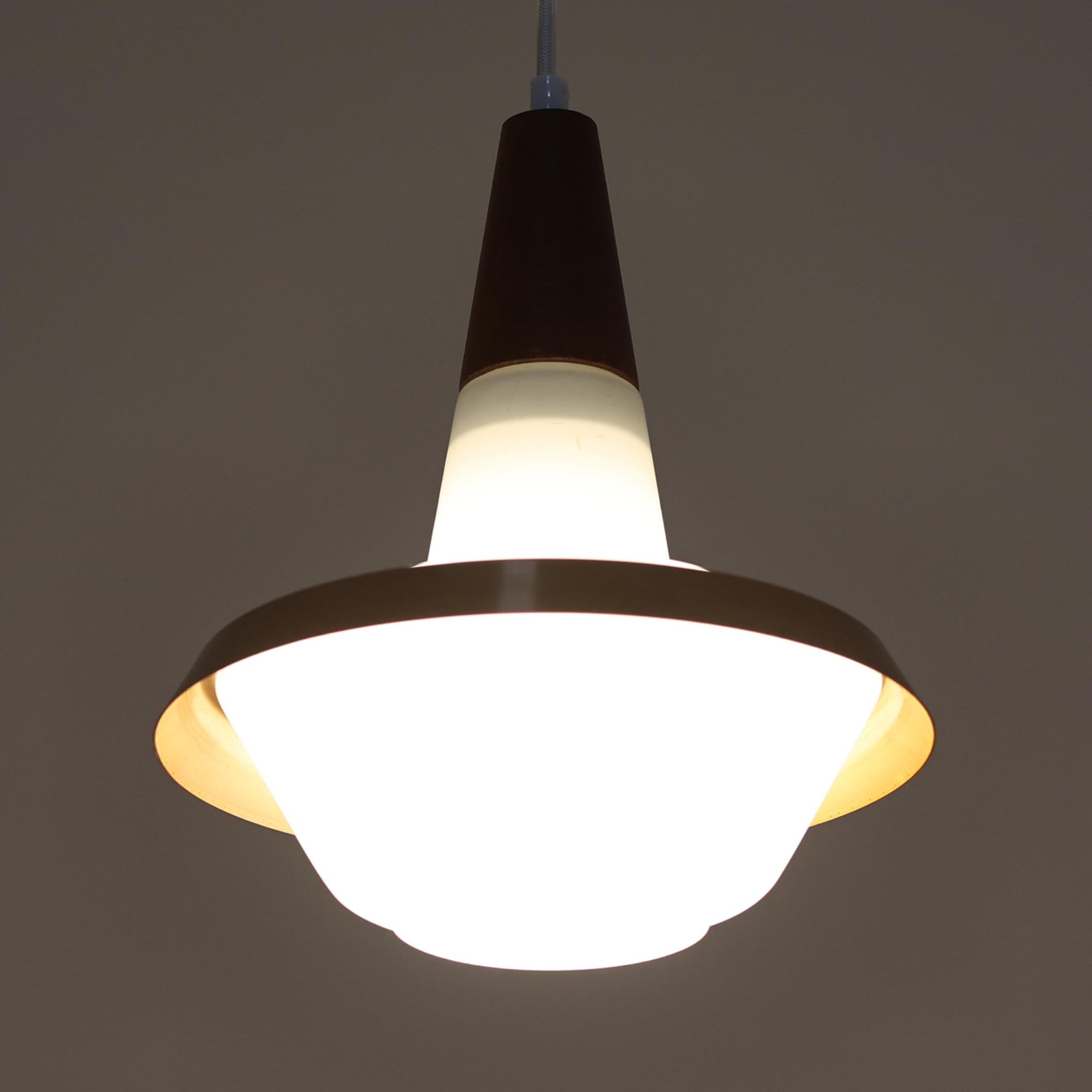 デンマーク製のペンダントライト、直径25cmです。ガラスシェードにチーク材とアルミのパーツを組み合わせた構造は、素材の質感を引き立てながら温かみのある北欧らしいデザインを感じさせます。ガラス越しに広がる柔らかな光は空間を優しく照らし、ダイニングやリビングの照明として心地よい雰囲気を演出します。経年によって深みを増したチーク材や金属部分の風合いはビンテージ品ならではの魅力であり、現行品にはない独自の存在感を楽しめる逸品です。