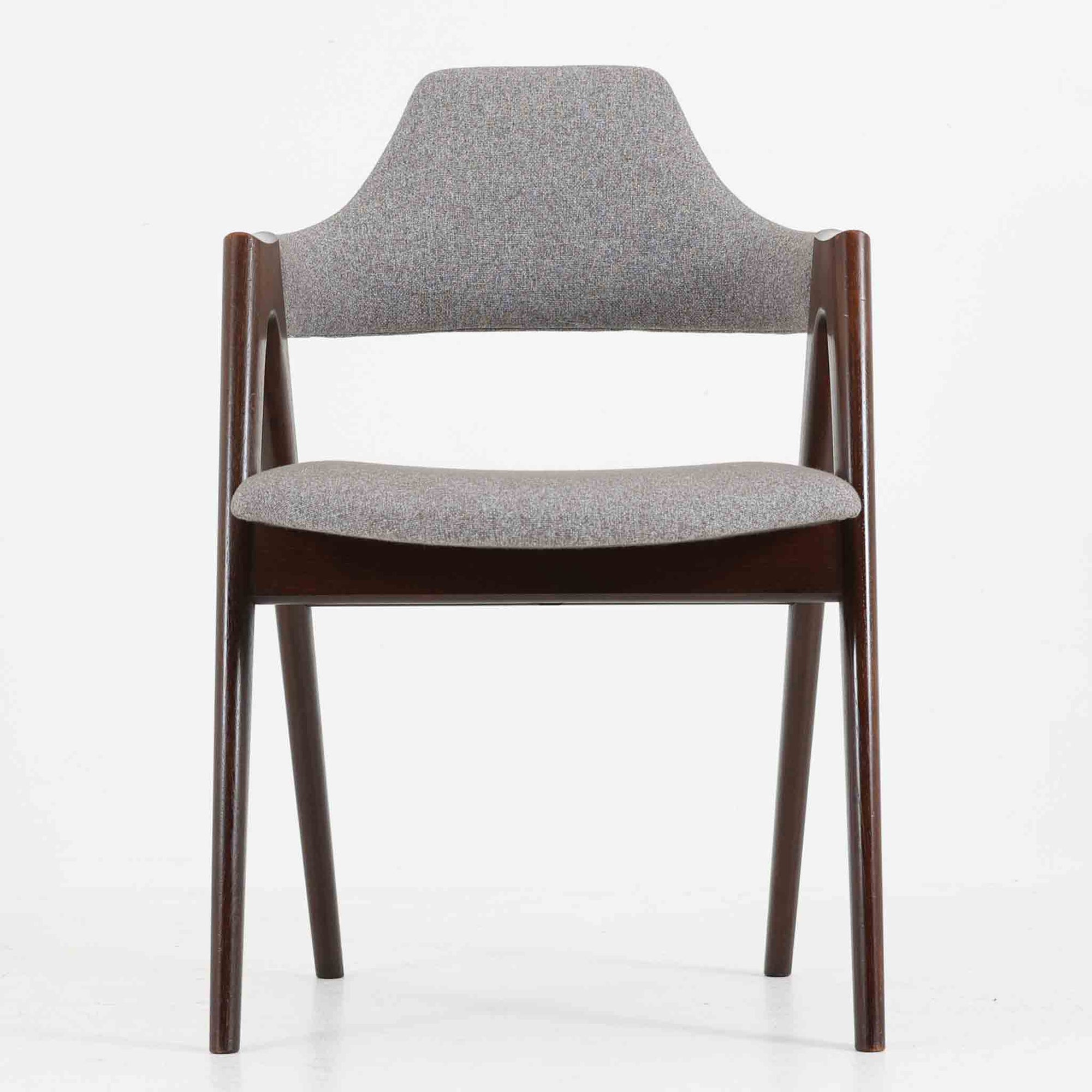デンマークのデザイナー、Kai Kristiansen（カイ・クリスチャンセン）による「コンパスチェア」。SVA Mobler社より製造された代表作のひとつです。名の通りコンパスの脚を思わせる美しい角度を持つフレーム構造が特徴で、木部にはステイン塗装された濃い色味のオーク材が使用されています。背もたれからアームへと流れるようなラインが柔らかく、身体を包み込むような快適な座り心地を実現。落ち着いたグレーの張地が空間に馴染みます。北欧デザインの美と機能が融合した名作チェアです。