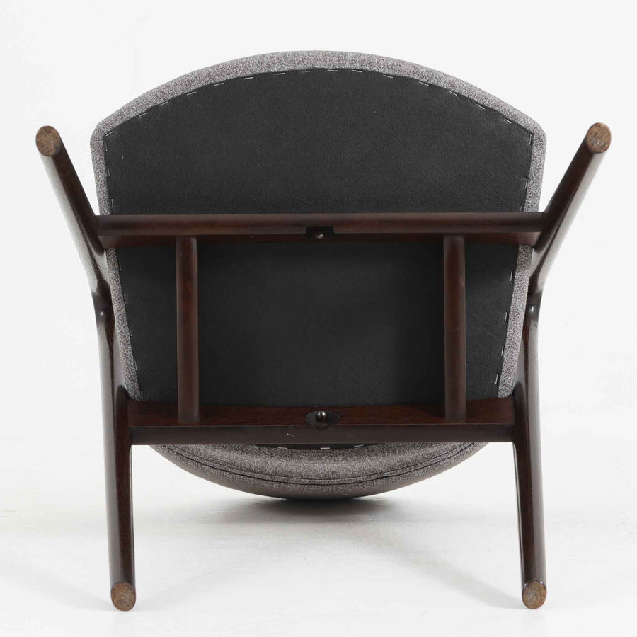 デンマークのデザイナー、Kai Kristiansen（カイ・クリスチャンセン）による「コンパスチェア」。SVA Mobler社より製造された代表作のひとつです。名の通りコンパスの脚を思わせる美しい角度を持つフレーム構造が特徴で、木部にはステイン塗装された濃い色味のオーク材が使用されています。背もたれからアームへと流れるようなラインが柔らかく、身体を包み込むような快適な座り心地を実現。落ち着いたグレーの張地が空間に馴染みます。北欧デザインの美と機能が融合した名作チェアです。