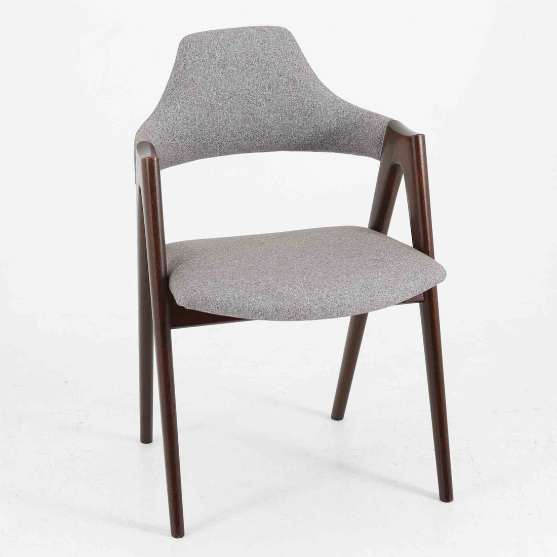 デンマークのデザイナー、Kai Kristiansen（カイ・クリスチャンセン）による「コンパスチェア」。SVA Mobler社より製造された代表作のひとつです。名の通りコンパスの脚を思わせる美しい角度を持つフレーム構造が特徴で、木部にはステイン塗装された濃い色味のオーク材が使用されています。背もたれからアームへと流れるようなラインが柔らかく、身体を包み込むような快適な座り心地を実現。落ち着いたグレーの張地が空間に馴染みます。北欧デザインの美と機能が融合した名作チェアです。