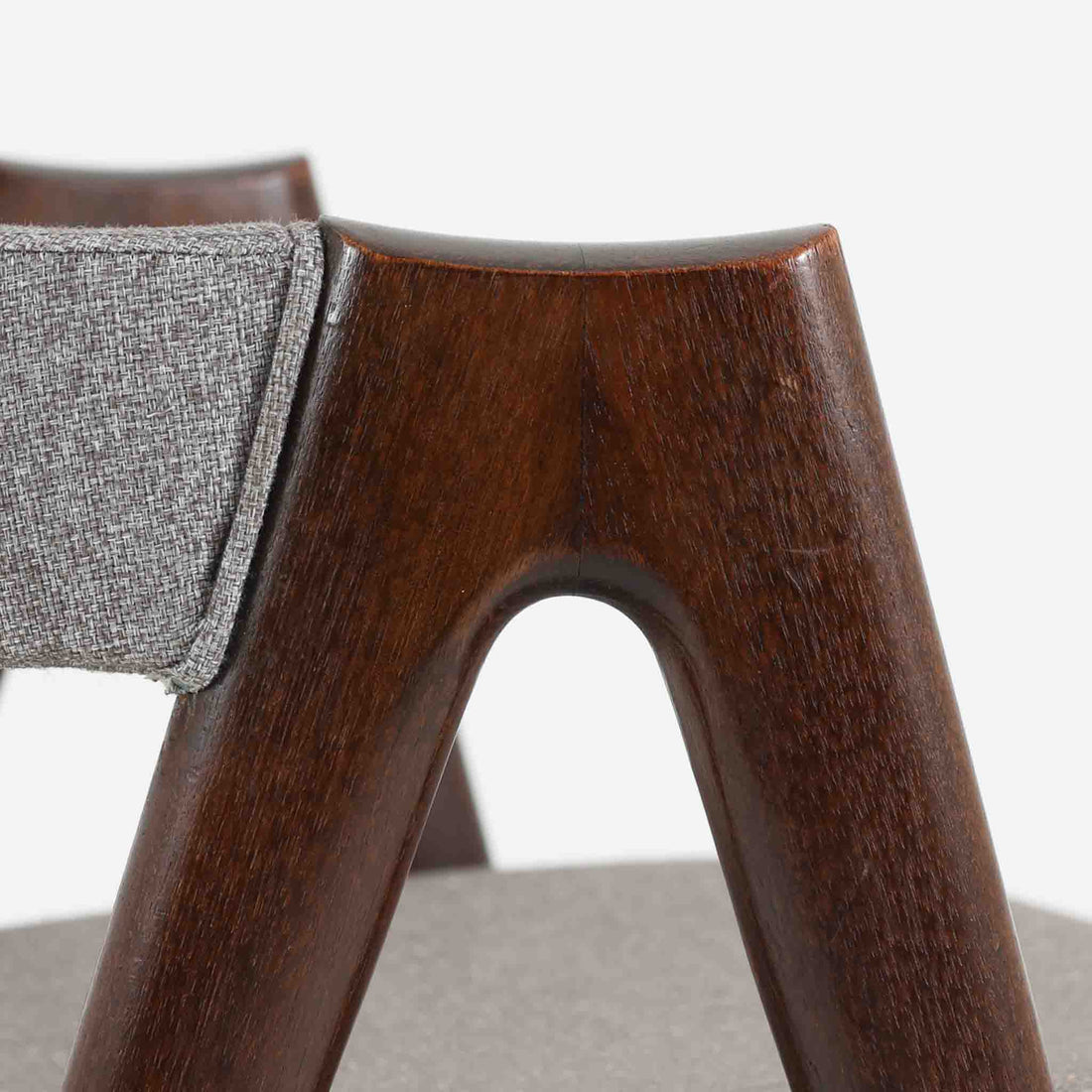 デンマークのデザイナー、Kai Kristiansen（カイ・クリスチャンセン）による「コンパスチェア」。SVA Mobler社より製造された代表作のひとつです。名の通りコンパスの脚を思わせる美しい角度を持つフレーム構造が特徴で、木部にはステイン塗装された濃い色味のオーク材が使用されています。背もたれからアームへと流れるようなラインが柔らかく、身体を包み込むような快適な座り心地を実現。落ち着いたグレーの張地が空間に馴染みます。北欧デザインの美と機能が融合した名作チェアです。