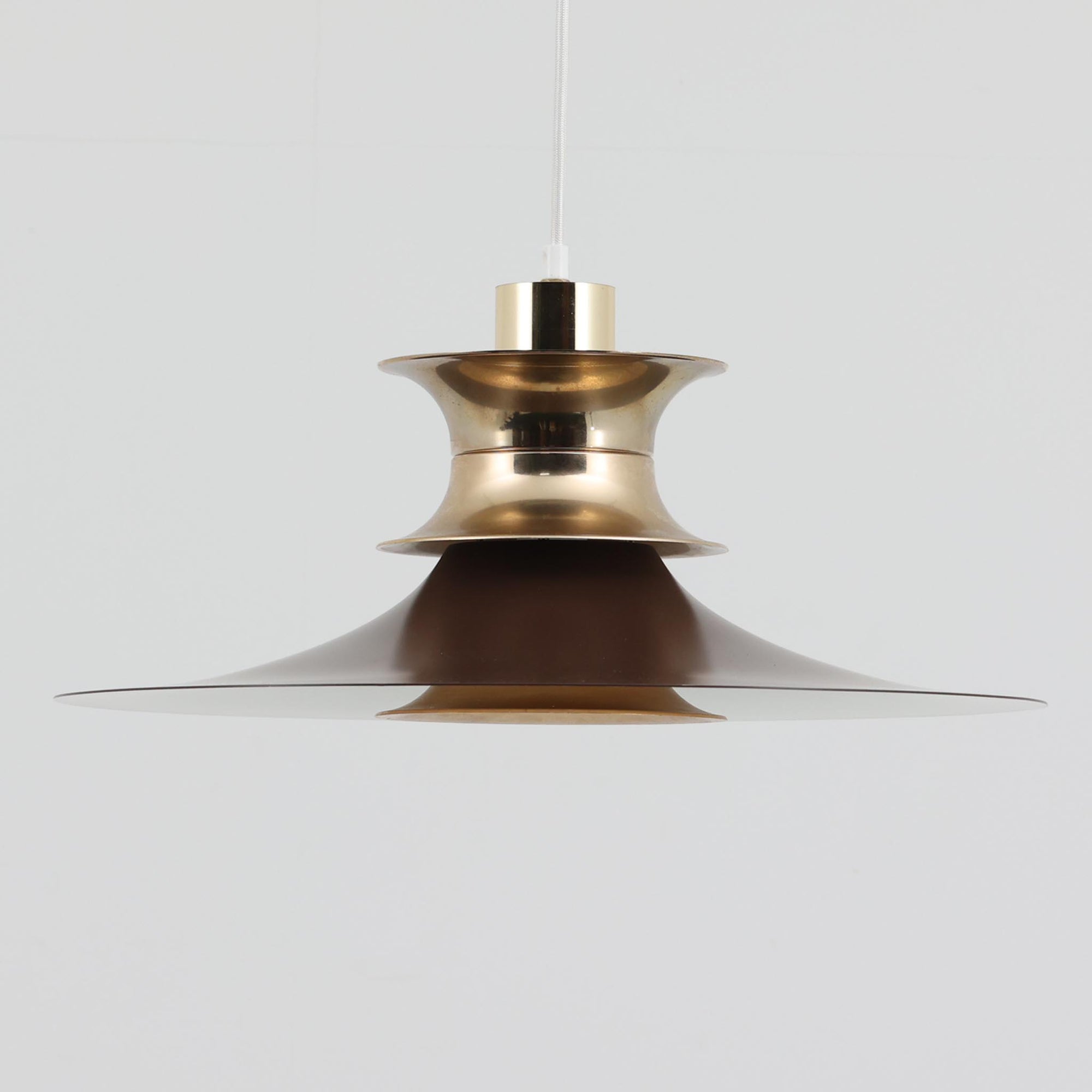 Strini Belysningによる本品は、直径49cmの大きめサイズが特徴のペンダントライトで、アルミ製シェードと真鍮色パーツのコントラストが美しい北欧ビンテージ品です。緩やかに広がるフォルムが光を柔らかく拡散し、ダイニングやリビングなど空間全体を穏やかに照らします。経年により深まった金属の質感がビンテージならではの存在感を放ち、シンプルな構造ながら職人技を感じさせる仕上げが魅力です。大きめのサイズ感を活かして天井から低めに吊るすと、インテリアの主役として空間に上質な雰囲気を添えてくれます。
