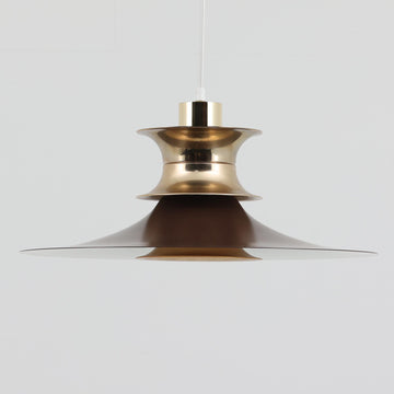 Strini Belysningによる本品は、直径49cmの大きめサイズが特徴のペンダントライトで、アルミ製シェードと真鍮色パーツのコントラストが美しい北欧ビンテージ品です。緩やかに広がるフォルムが光を柔らかく拡散し、ダイニングやリビングなど空間全体を穏やかに照らします。経年により深まった金属の質感がビンテージならではの存在感を放ち、シンプルな構造ながら職人技を感じさせる仕上げが魅力です。大きめのサイズ感を活かして天井から低めに吊るすと、インテリアの主役として空間に上質な雰囲気を添えてくれます。