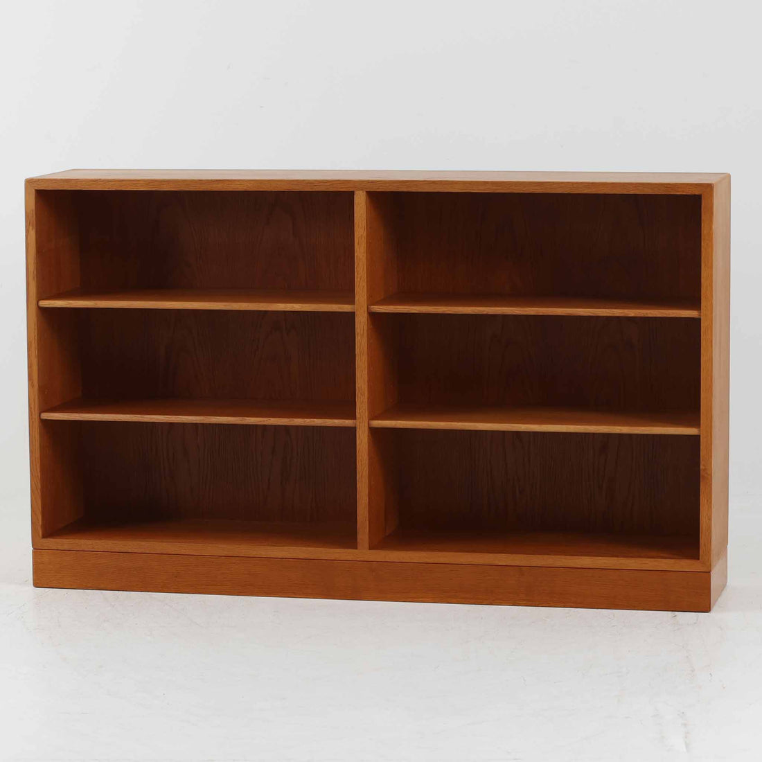 Borge Mogensen（ボーエ・モーエンセン）によるFDB社製のブックシェルフです。良質なオーク材で、温かみのある色合いと堅牢な造りが魅力です。幅122cmのワイドなサイズで、書籍や雑誌の収納はもちろん、オブジェやコレクションのディスプレイにも適しています。シンプルで直線的なフォルムは北欧家具らしい機能美を感じさせ、経年によって増した深い色艶がビンテージならではの存在感を放ちます。書斎やリビングにおいて実用性と美観を兼ね備えた一台です。