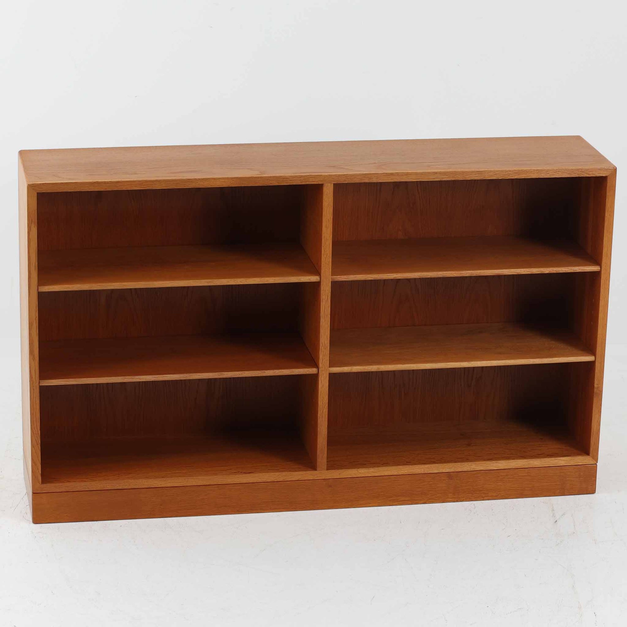 Borge Mogensen（ボーエ・モーエンセン）によるFDB社製のブックシェルフです。良質なオーク材で、温かみのある色合いと堅牢な造りが魅力です。幅122cmのワイドなサイズで、書籍や雑誌の収納はもちろん、オブジェやコレクションのディスプレイにも適しています。シンプルで直線的なフォルムは北欧家具らしい機能美を感じさせ、経年によって増した深い色艶がビンテージならではの存在感を放ちます。書斎やリビングにおいて実用性と美観を兼ね備えた一台です。