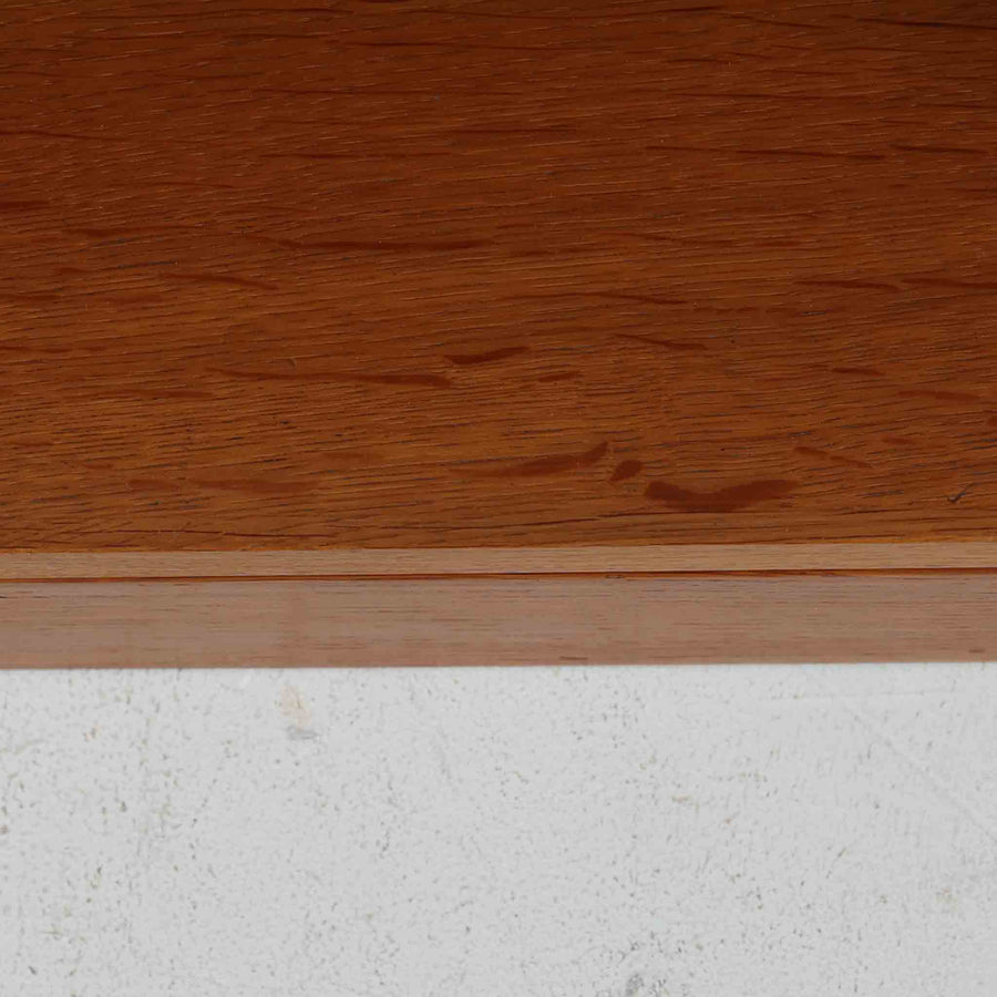 Borge Mogensen（ボーエ・モーエンセン）によるFDB社製のブックシェルフです。良質なオーク材で、温かみのある色合いと堅牢な造りが魅力です。幅122cmのワイドなサイズで、書籍や雑誌の収納はもちろん、オブジェやコレクションのディスプレイにも適しています。シンプルで直線的なフォルムは北欧家具らしい機能美を感じさせ、経年によって増した深い色艶がビンテージならではの存在感を放ちます。書斎やリビングにおいて実用性と美観を兼ね備えた一台です。