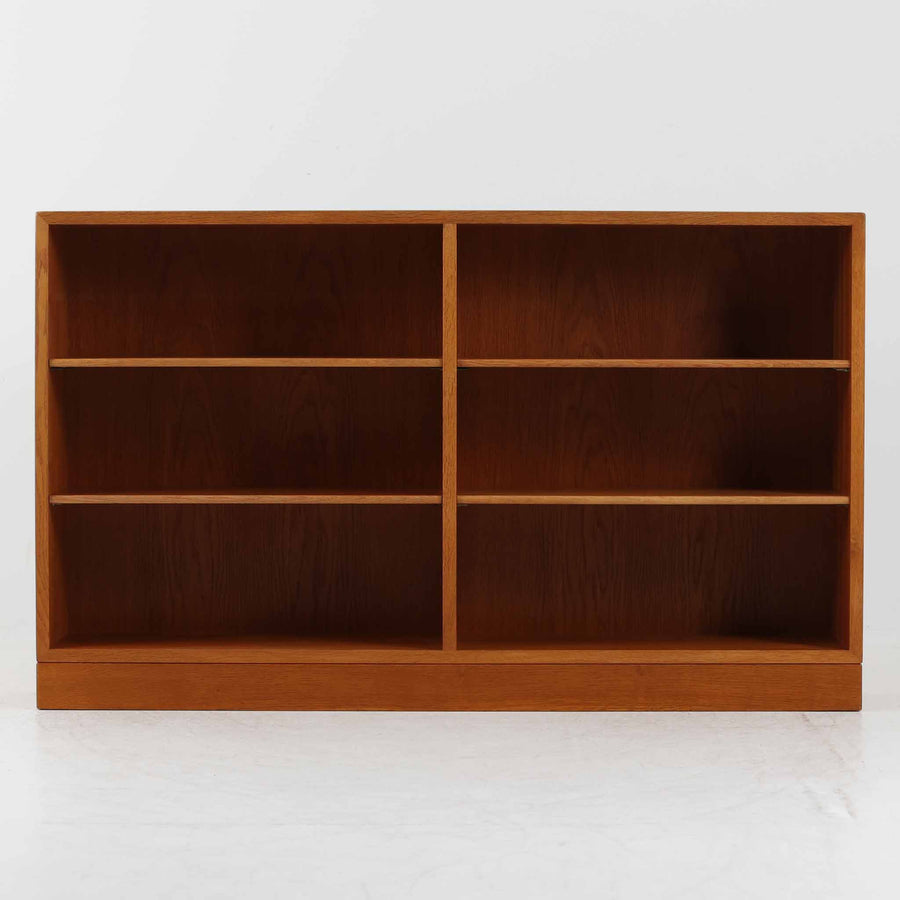 Borge Mogensen（ボーエ・モーエンセン）によるFDB社製のブックシェルフです。良質なオーク材で、温かみのある色合いと堅牢な造りが魅力です。幅122cmのワイドなサイズで、書籍や雑誌の収納はもちろん、オブジェやコレクションのディスプレイにも適しています。シンプルで直線的なフォルムは北欧家具らしい機能美を感じさせ、経年によって増した深い色艶がビンテージならではの存在感を放ちます。書斎やリビングにおいて実用性と美観を兼ね備えた一台です。