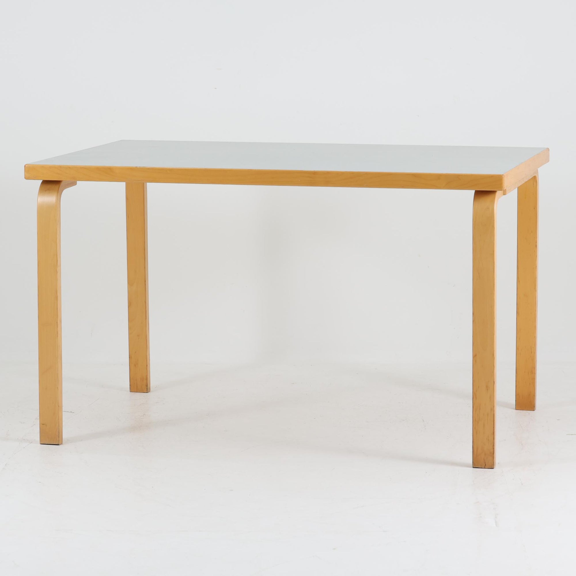 Alvar AaltoがデザインしArtek社より製造されたこちらのダイニングテーブルは、天板に落ち着いたグレートーンのリノリウム、脚部に美しい木肌のバーチ材を用いた北欧モダンデザインの名作で、L字型に曲げられた脚部がアアルトらしい柔らかな造形美を感じさせます。幅120cmの使い勝手のよいサイズ感で、ダイニングやワークスペースにもしっくりと馴染み、天板裏面には脚の付け替え跡が見られ、アアルト製品が多く採用されていたデンマークの公共施設で丁寧に使用されていた個体です。機能美と素材感のバランスに優れた一台です。