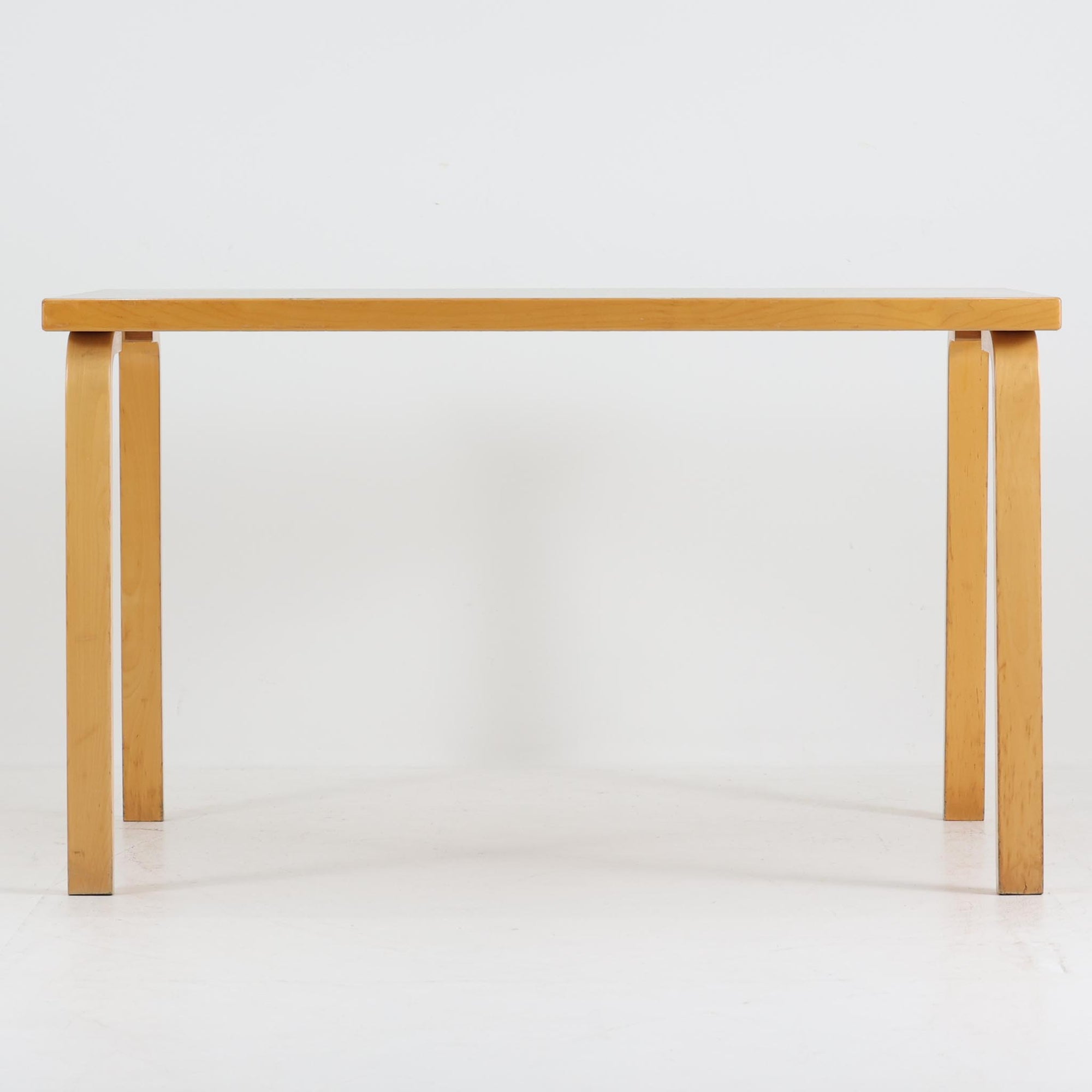 Alvar AaltoがデザインしArtek社より製造されたこちらのダイニングテーブルは、天板に落ち着いたグレートーンのリノリウム、脚部に美しい木肌のバーチ材を用いた北欧モダンデザインの名作で、L字型に曲げられた脚部がアアルトらしい柔らかな造形美を感じさせます。幅120cmの使い勝手のよいサイズ感で、ダイニングやワークスペースにもしっくりと馴染み、天板裏面には脚の付け替え跡が見られ、アアルト製品が多く採用されていたデンマークの公共施設で丁寧に使用されていた個体です。機能美と素材感のバランスに優れた一台です。