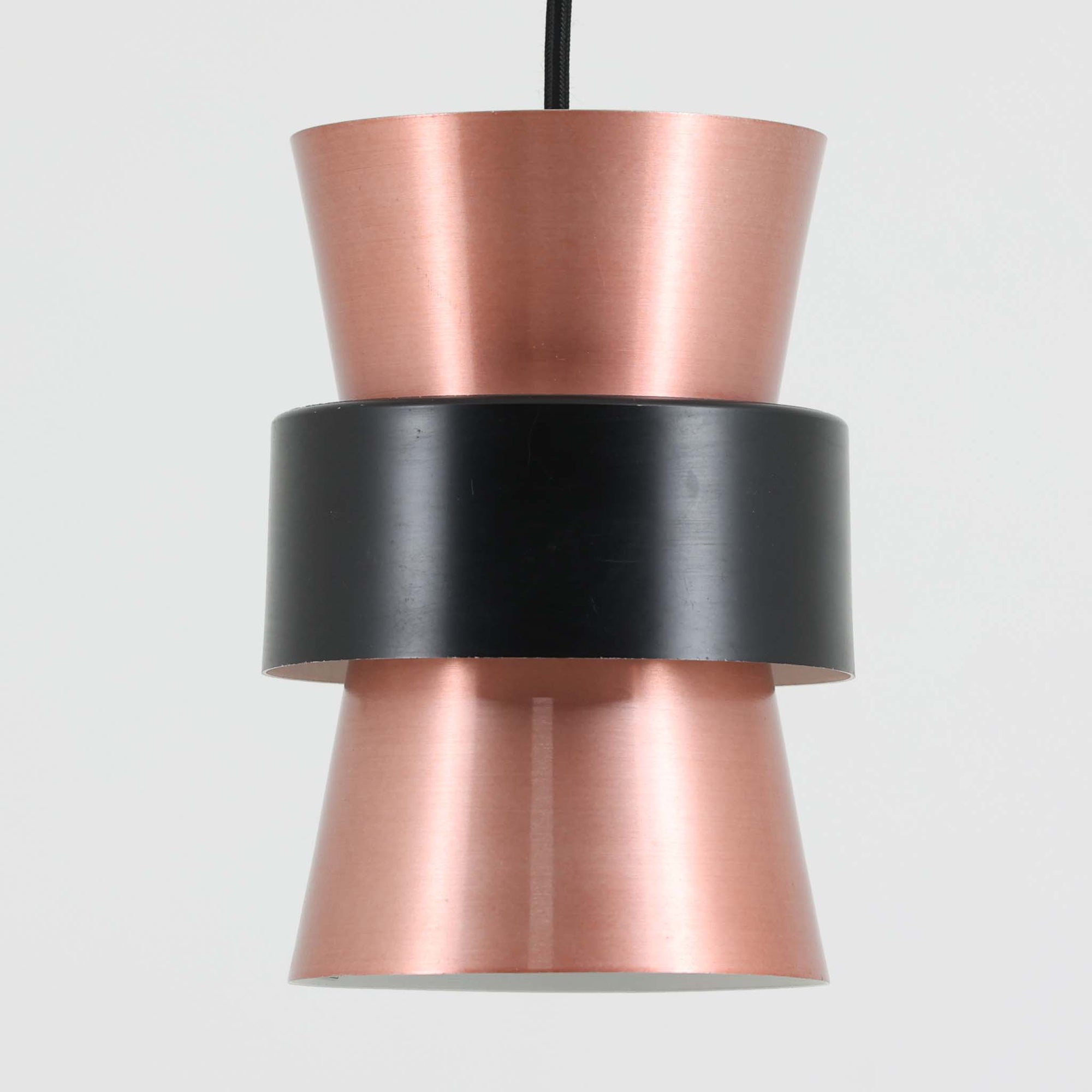 Jo HammerborgがFog & Morup社のためにデザインした直径14cmの小ぶりなペンダントライトです。アルミ製のシェードは上下に広がる砂時計のようなフォルムに、中央のブラックバンドがアクセントとなったモダンなデザイン。点灯時には光が上下にやわらかく広がり、陰影の美しい表情を見せます。コンパクトサイズのためダイニングで複数吊り下げての使用や、玄関・書斎のポイントライトとしても活躍。北欧ビンテージ照明ならではの洗練された存在感を放ちます。