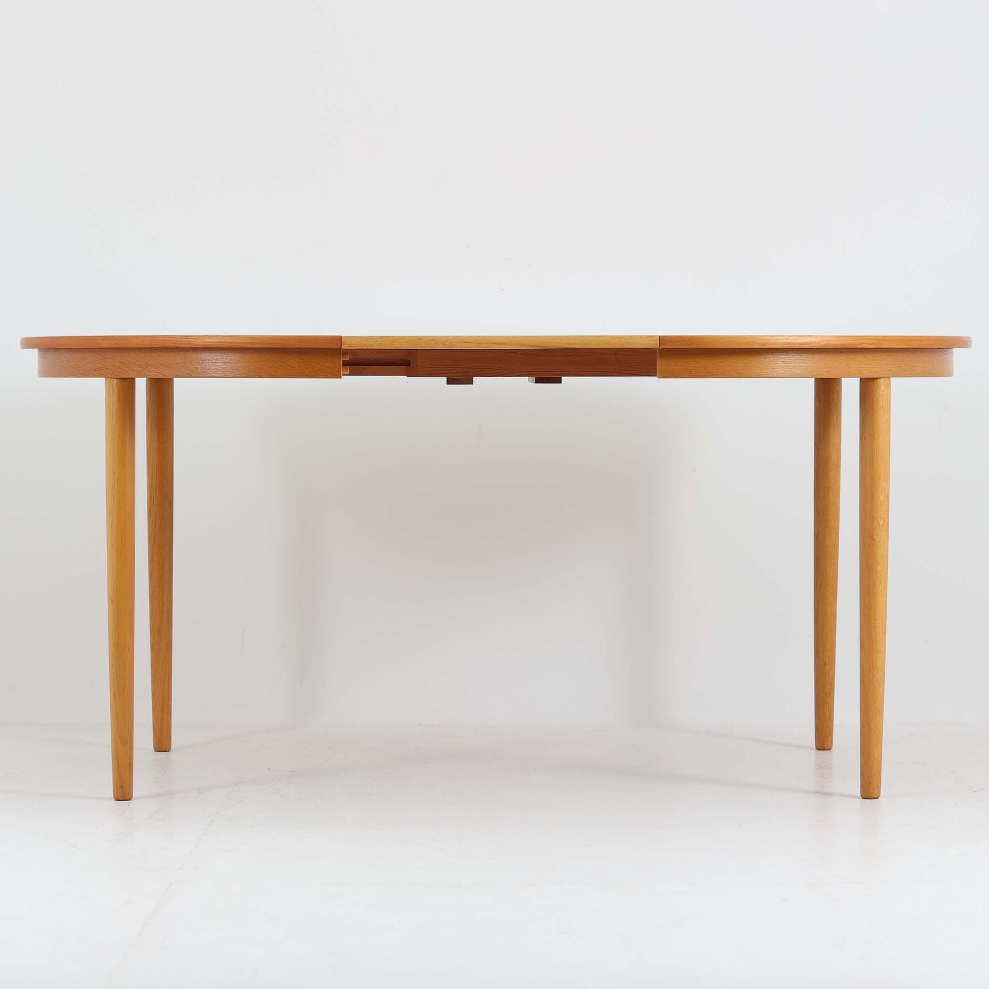 デンマークの老舗家具メーカー、Farstrup Mobler（ファストラップ・モブラー）による円形エクステンションダイニングテーブルです。オーク材の優しい色合いと美しい木目が際立ち、北欧家具らしい明るく軽やかな雰囲気を演出します。円形の天板は互いの距離が自然と近づき、家族や友人との会話が弾む柔らかな空間を生み出します。中央の拡張板を取り付けることで人数や用途に応じてサイズ調整が可能で、普段使いにも来客時にも活躍。テーパー脚のバランスが美しく、シンプルながらも洗練されたデザインが魅力です。温もりある素材感と丁寧な仕上げが、日常の食卓を心地よい時間へと導いてくれます。