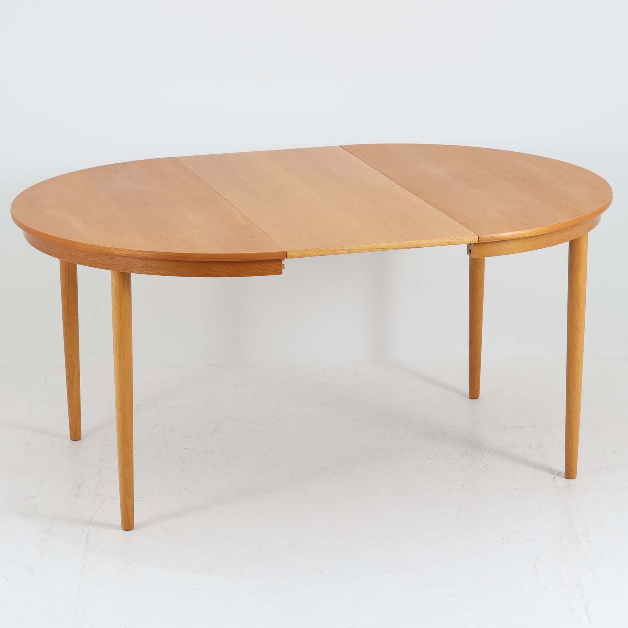 デンマークの老舗家具メーカー、Farstrup Mobler（ファストラップ・モブラー）による円形エクステンションダイニングテーブルです。オーク材の優しい色合いと美しい木目が際立ち、北欧家具らしい明るく軽やかな雰囲気を演出します。円形の天板は互いの距離が自然と近づき、家族や友人との会話が弾む柔らかな空間を生み出します。中央の拡張板を取り付けることで人数や用途に応じてサイズ調整が可能で、普段使いにも来客時にも活躍。テーパー脚のバランスが美しく、シンプルながらも洗練されたデザインが魅力です。温もりある素材感と丁寧な仕上げが、日常の食卓を心地よい時間へと導いてくれます。