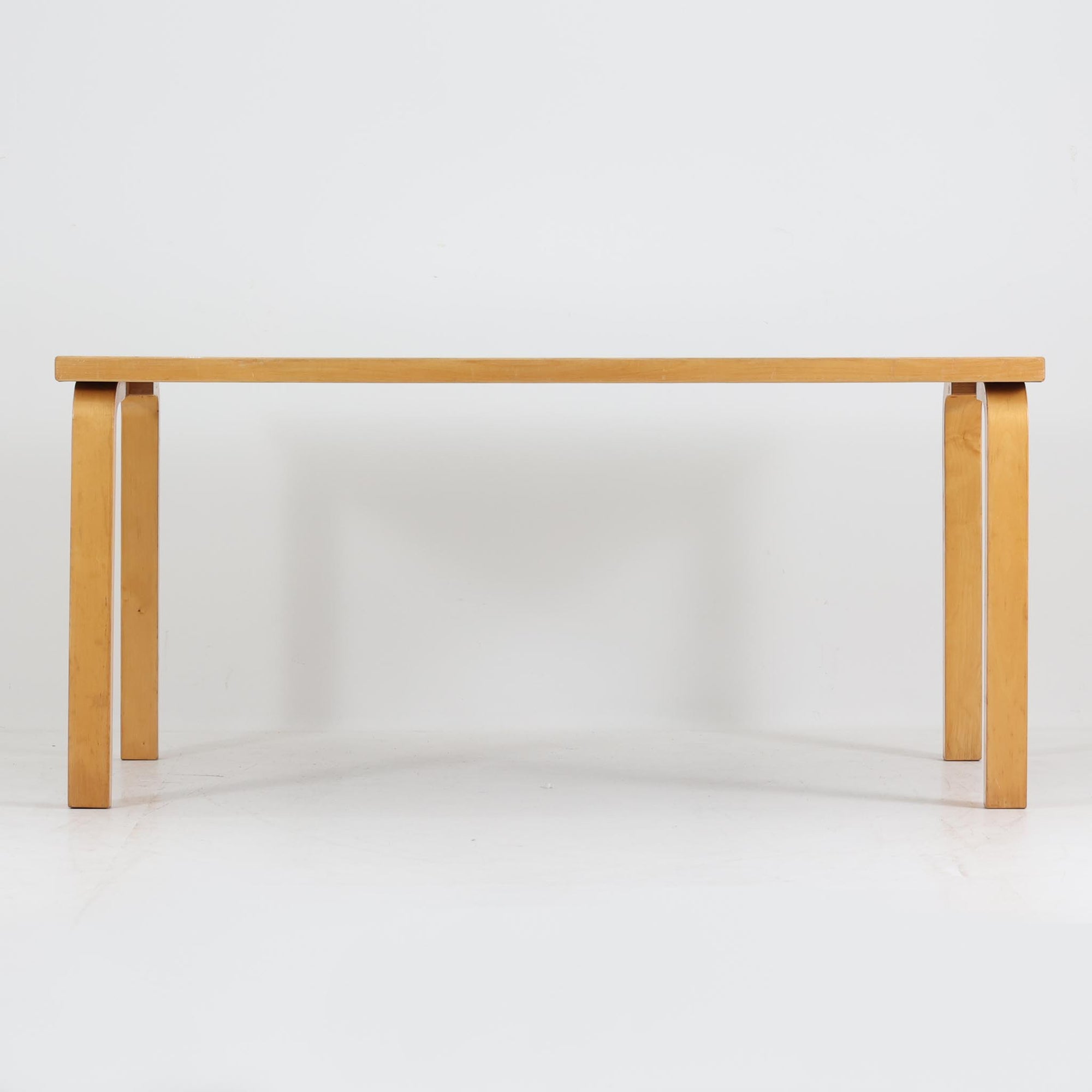 Alvar AaltoがデザインしArtek社より製造されたこちらのダイニングテーブルは、フィンランドモダニズムを象徴する一本。バーチ材の脚部に柔らかくカーブを描くLレッグ構造が取り入れられ、軽やかでありながらも高い強度を実現しています。天板は実用性に優れたホワイトラミネート仕上げで、幅150cmのゆとりあるサイズは家族での食卓やワークスペースにも最適です。幕板の一部に交換がありますが、アアルト製品が多く採用されていたデンマークの公共施設で丁寧に使用されていた個体です。