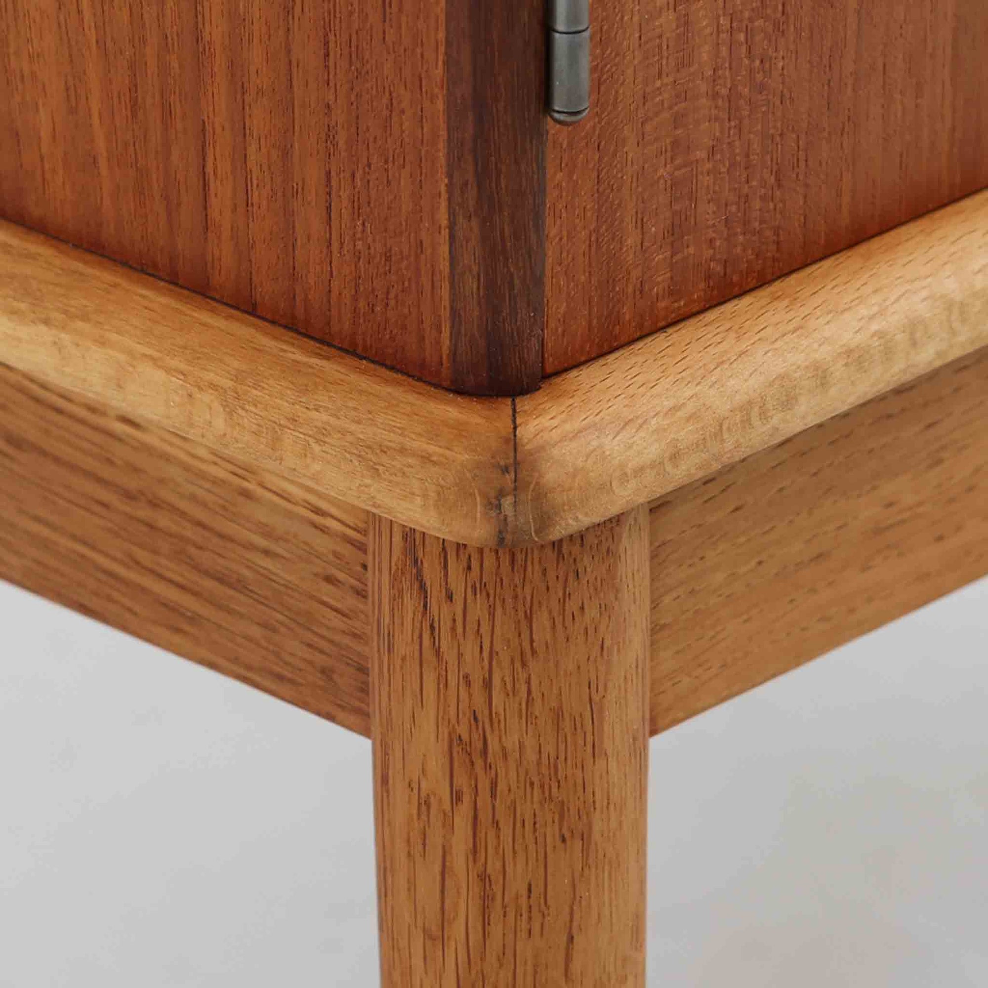 デンマーク製の小ぶりなキャビネットです。チーク材をメインに、オーク材やビーチ材を組み合わせることで、温かみのある色調と軽快な雰囲気を併せ持っています。左側は扉付き収納、右側には3杯の引き出しを備え、実用性とデザイン性を両立。丸みを帯びた取っ手や脚部のテーパーラインが北欧家具らしい柔らかな印象を与えます。幅63cmとコンパクトなサイズで、リビングや寝室、玄関など限られたスペースでも活躍する、ビンテージならではの風合いを持つ一台です。