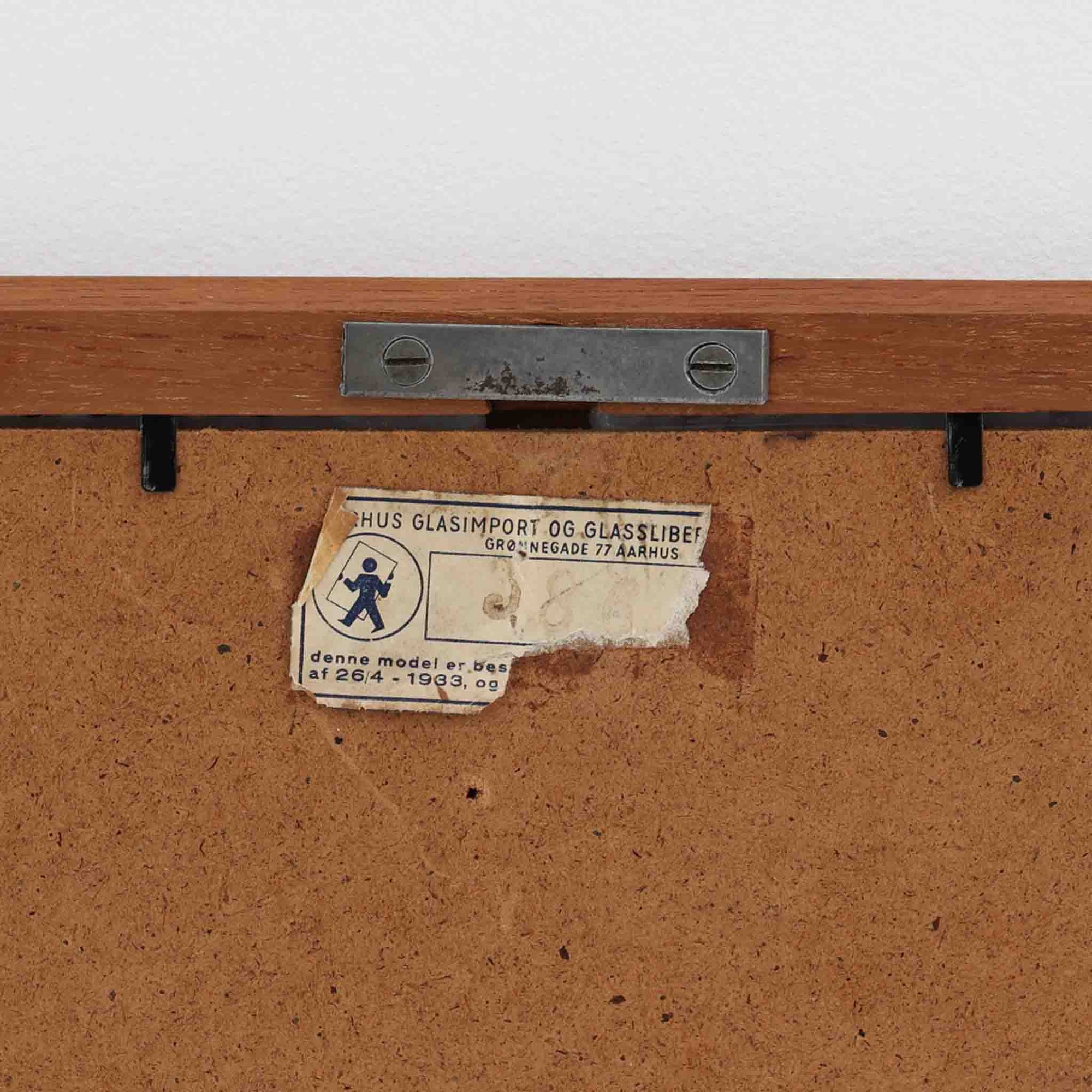 デンマークのAarhus Glasimport og Glassliberi社製による、チーク材フレームの壁掛け／立掛けミラーです。上部がわずかに広がる特徴的な台形フォルムが印象的で、やわらかな曲線を描くフレームが北欧デザインらしい優美さを感じさせます。チーク材のあたたかみのある色合いと美しい木目が空間に自然と溶け込み、玄関や寝室、リビングなどさまざまなシーンで活躍します。経年により深みを増した風合いが、北欧ビンテージらしい落ち着いた存在感を放つ一品です。