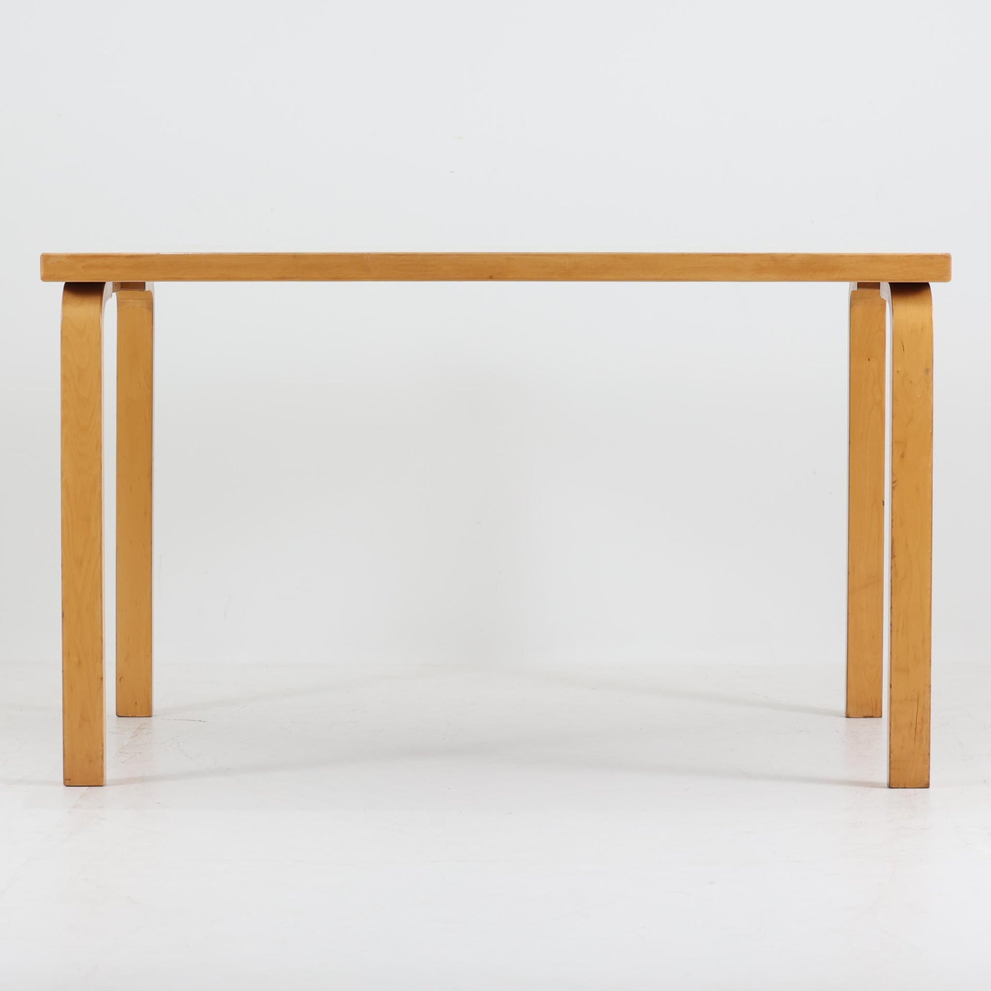 フィンランドの建築家Alvar Aaltoがデザインし、Artek社から製造されたダイニングテーブルです。温かみのあるバーチ材の脚と、耐久性に優れたホワイトラミネート天板の組み合わせが印象的で、Aalto特有の柔らかな曲線を描く脚部が、空間に優しい印象を与えます。幅120cmの扱いやすいサイズ感は、2〜4人での使用に適しており、ダイニングはもちろんワークデスクとしての活用もおすすめです。素材や構造に見られる北欧モダンデザインの美学と、長い年月を経た木部の風合いが魅力の一台です。