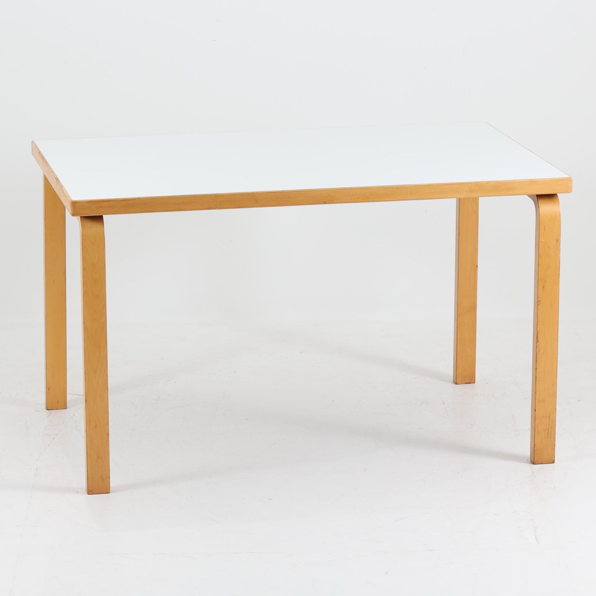 フィンランドの建築家Alvar Aaltoがデザインし、Artek社から製造されたダイニングテーブルです。温かみのあるバーチ材の脚と、耐久性に優れたホワイトラミネート天板の組み合わせが印象的で、Aalto特有の柔らかな曲線を描く脚部が、空間に優しい印象を与えます。幅120cmの扱いやすいサイズ感は、2〜4人での使用に適しており、ダイニングはもちろんワークデスクとしての活用もおすすめです。素材や構造に見られる北欧モダンデザインの美学と、長い年月を経た木部の風合いが魅力の一台です。