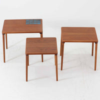 チーク材の温かみある木肌に、落ち着いたブルー系陶磁器タイルをあしらったネストテーブルは、北欧ビンテージらしい実用性と装飾性を兼ね備えたセットです。大小3台を重ねて収納できる合理的な構造で、必要に応じてサイドテーブルや補助台として柔軟に使い分けが可能。角を丸く仕上げた天板や細身の脚部には丁寧な木工技術が感じられ、経年により深みを増した表情が空間に静かな存在感を添えます。