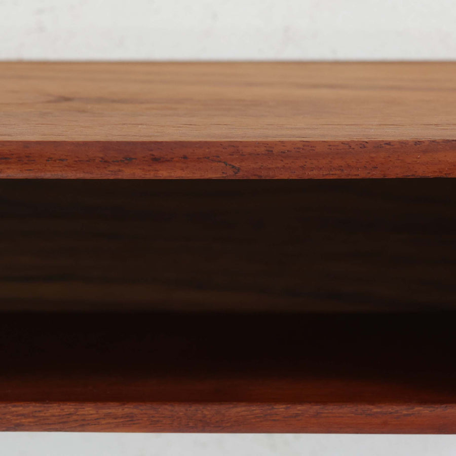 デンマーク製ウォールシェルフです。上質なチーク無垢材を使用し、滑らかなカーブを描く縁取りと丸みのあるフォルムが北欧家具らしい柔らかさを感じさせます。奥行きを抑えたコンパクトなサイズで、玄関や寝室、リビングのちょっとしたスペースにも取り付けやすい設計です。経年により深みを増したチーク材の美しい色合いが、壁面を上品に演出します。