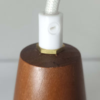 デンマーク製のペンダントライト、直径13cmです。ガラスシェードには立体的なドット模様が施され、点灯すると陰影が浮かび上がり独特の表情を生み出します。上部にはチーク材が用いられ、ガラスの繊細さと木の温もりが調和した北欧らしい意匠が魅力です。小ぶりなサイズながらも存在感があり、キッチンや廊下、ベッドサイドなど複数使いにも適しています。経年による素材の風合いがビンテージ品ならではの味わいを感じさせ、日常空間に個性を添える一品です。