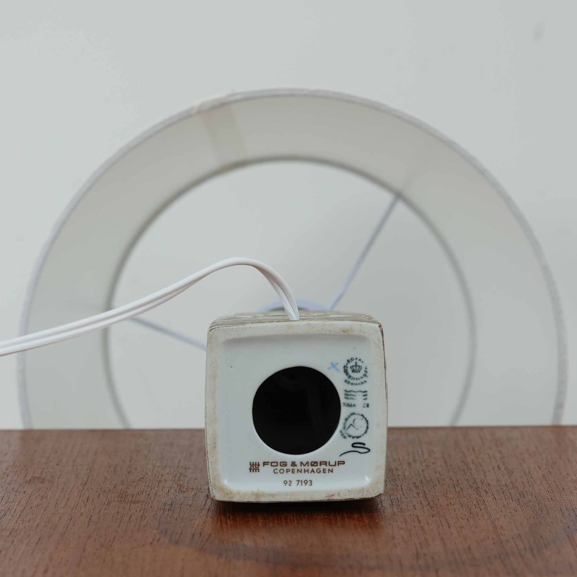 Nils Thorssonがデザインし、Royal Copenhagen社から発表された「BACA」シリーズのテーブルランプは、高さ39cmのバランスの取れたサイズ感で、北欧ビンテージらしい存在感を放ちます。陶磁器製のベースには細やかな装飾模様が施され、グラフィカルでありながら落ち着いた色調が空間に洗練された雰囲気を添えます。リネンシェードを透過する柔らかな光が温もりを演出し、リビングやベッドサイドに最適です。年月を経て深みを増した質感と工芸的な美しさを楽しめる一点物です。