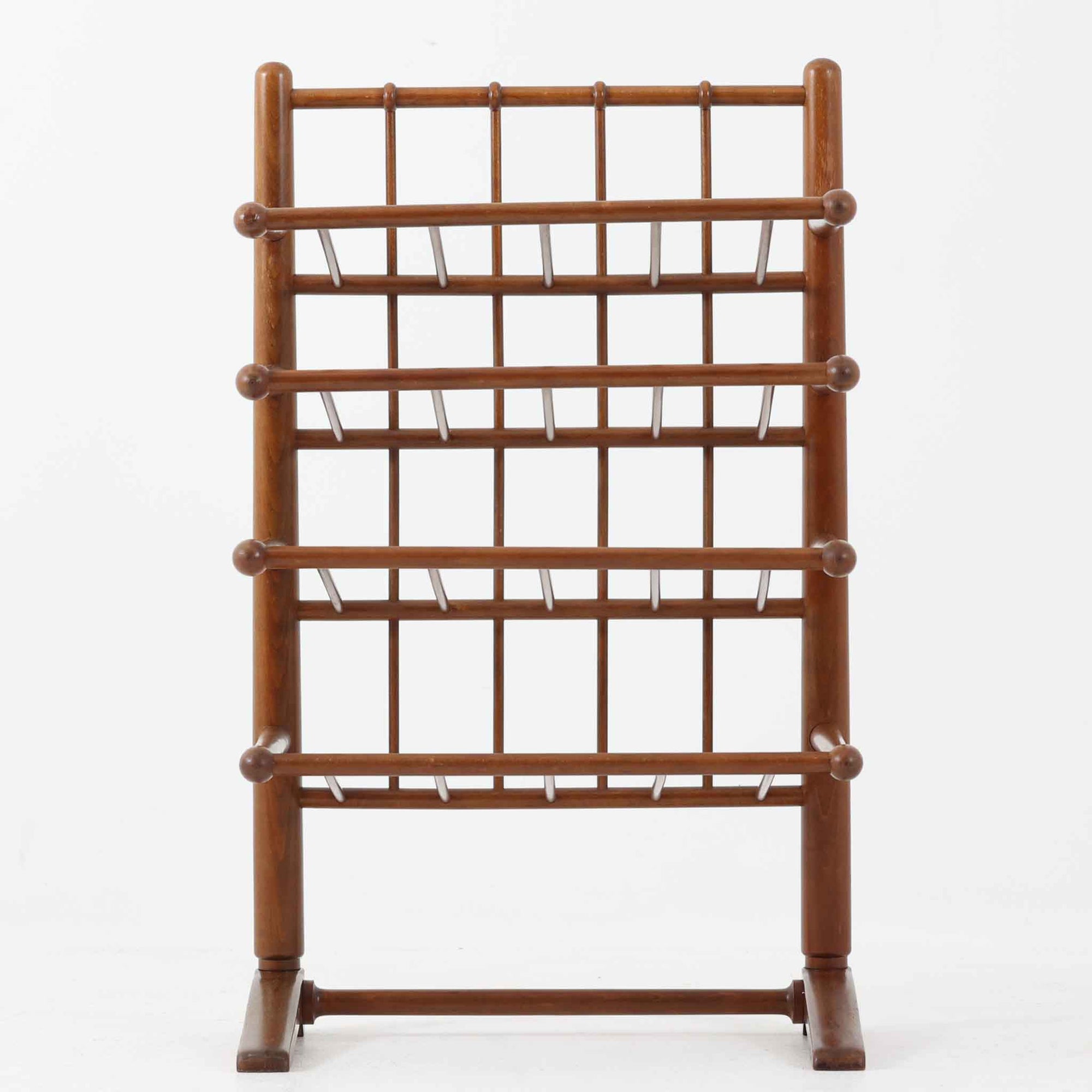 Frits Henningsenによってデザインされ、Andreas Tuck社から製造されたこちらのマガジンラックは、ビーチ材にステイン仕上げを施した温かみのある北欧ビンテージ家具です。前方に傾斜した4段構造の棚は、それぞれに仕切りがあり、雑誌や新聞を分類して収納しやすい設計となっています。丸みを帯びた支柱や棚先端の球状意匠に職人の丁寧な手仕事が感じられ、空間に柔らかな存在感を添える名作家具です。