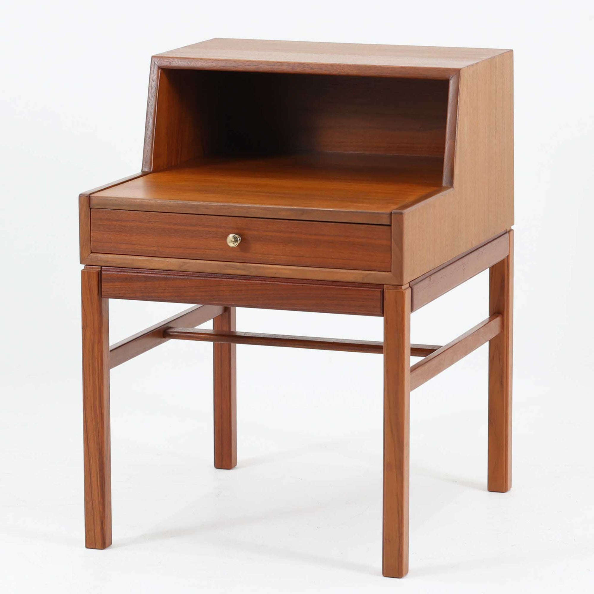 デンマーク製の北欧ビンテージサイドチェストです。チーク材の落ち着いた色合いと美しい木目が際立ち、奥行きをしっかりと確保した設計が実用性を高めています。上部はオープンスペースと、下段には小ぶりな引き出しを配置。真鍮調のつまみがさりげないアクセントとなり、直線的なフォルムとすらりとした脚部が軽やかな印象を与えます。ベッドサイドやリビングでの小物収納、簡易デスクとしても活躍し、経年による艶やかな風合いが空間に温もりを添える一台です。